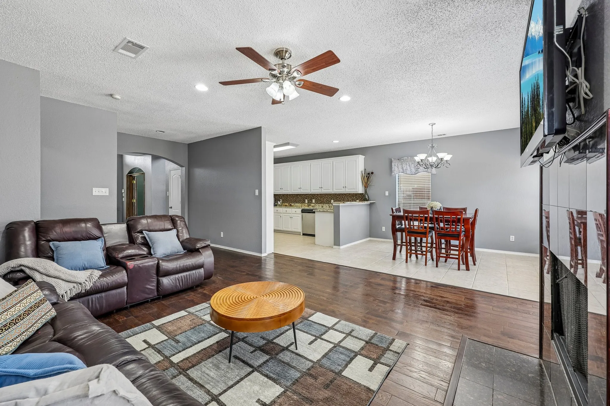 Open-concept living space featuring wood-finish flooring, recessed lighting, and a ceiling fan