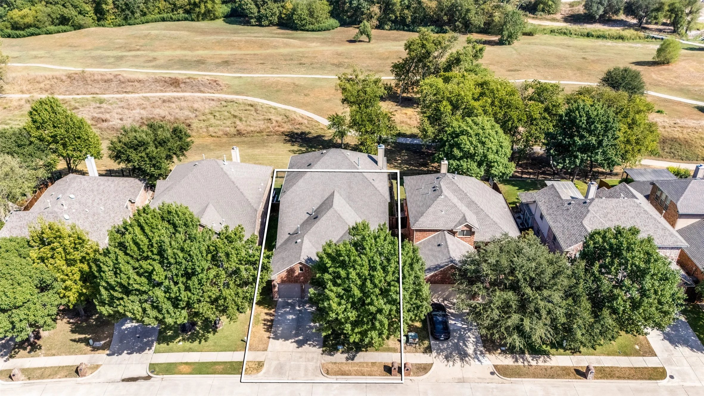 Property with a gabled roofline, mature trees, and a concrete driveway