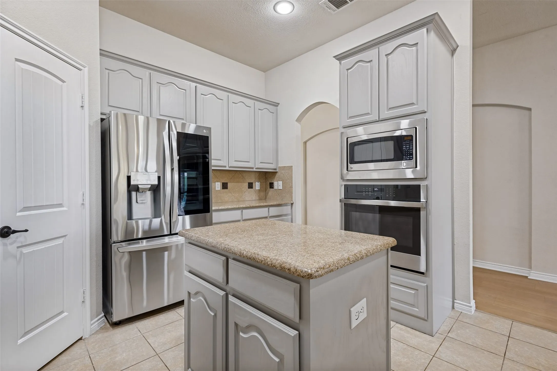 Kitchen featuring an island, light-toned cabinetry, stainless steel appliances, and tiled flooring