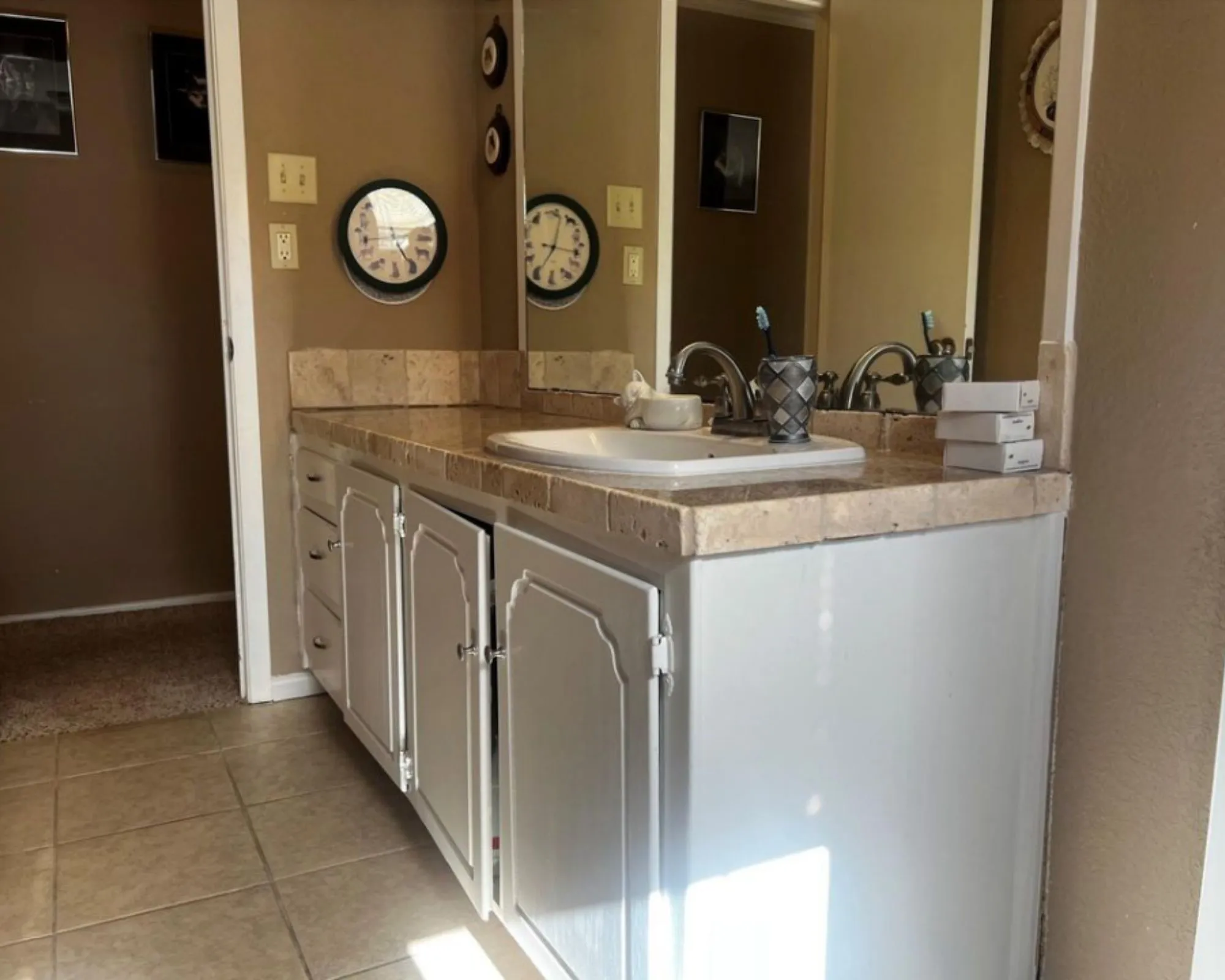 Vanity with a tiled countertop, integrated sink, and white cabinetry featuring decorative paneling