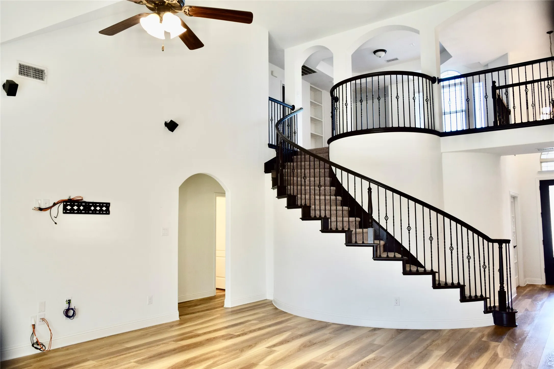 Stairway with ceiling fan, a towering ceiling, and wood-type flooring