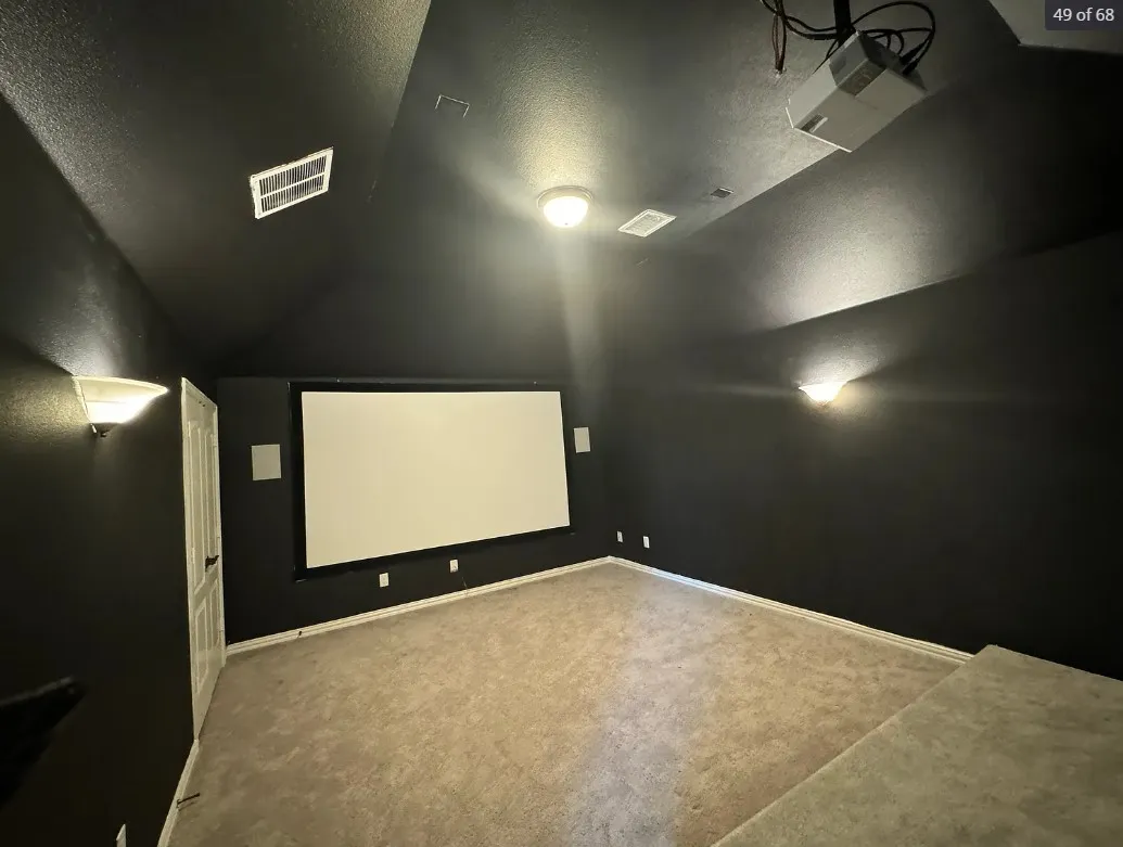 Home theater room featuring lofted ceiling, a textured ceiling, and carpet floors