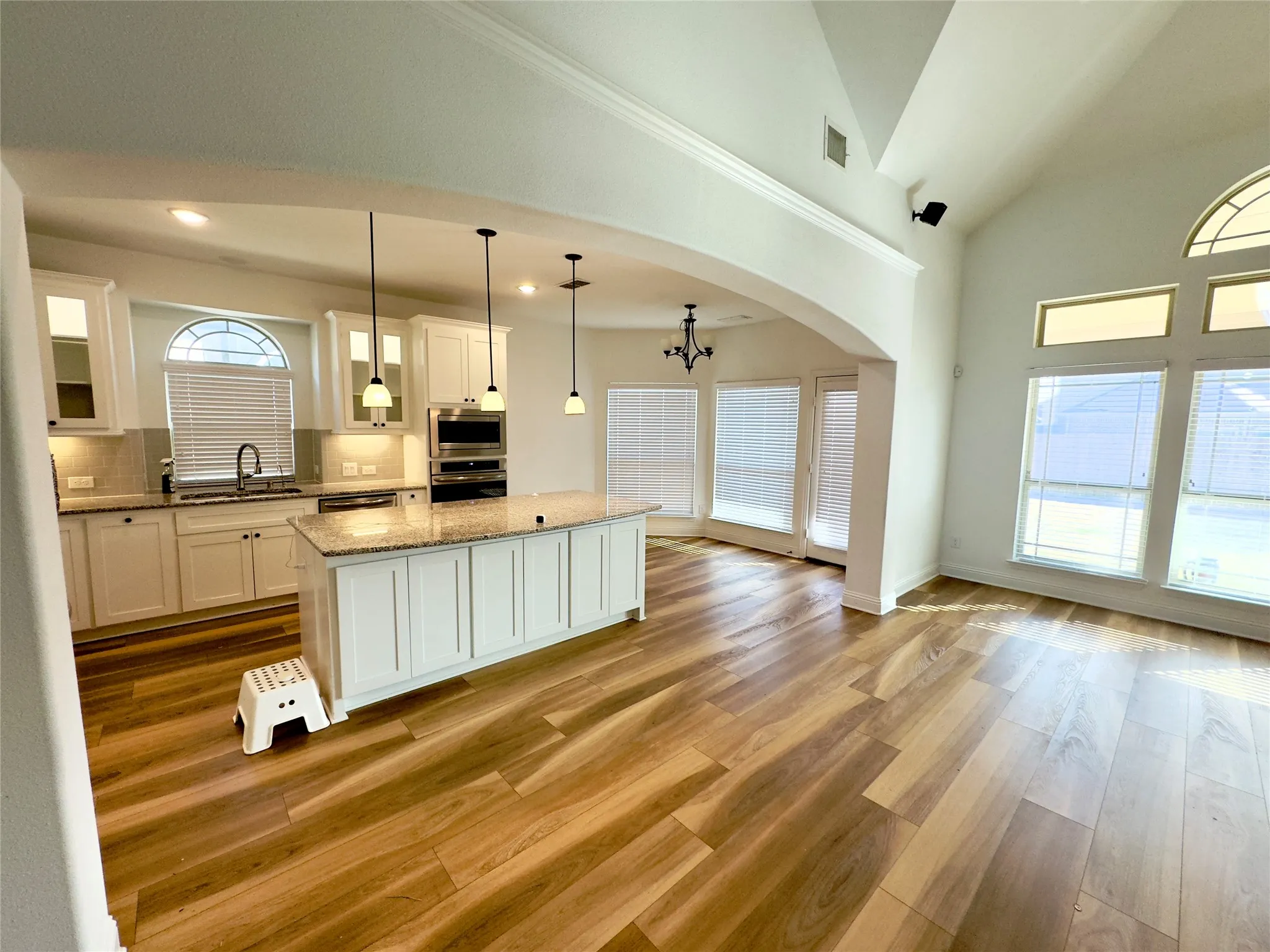 Kitchen with white cabinets, tasteful backsplash, a kitchen island, and pendant lighting