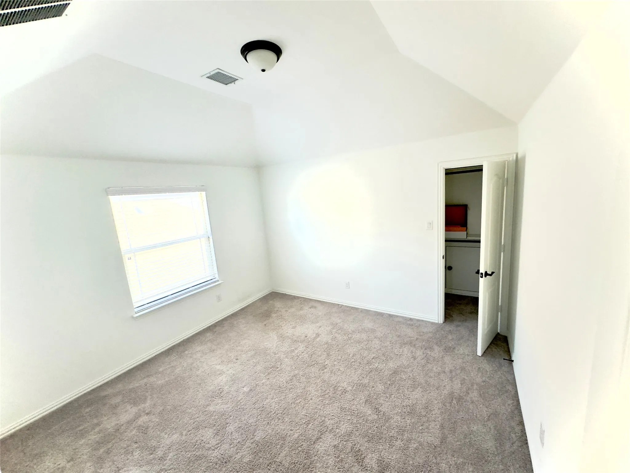 Unfurnished bedroom with lofted ceiling and light colored carpet