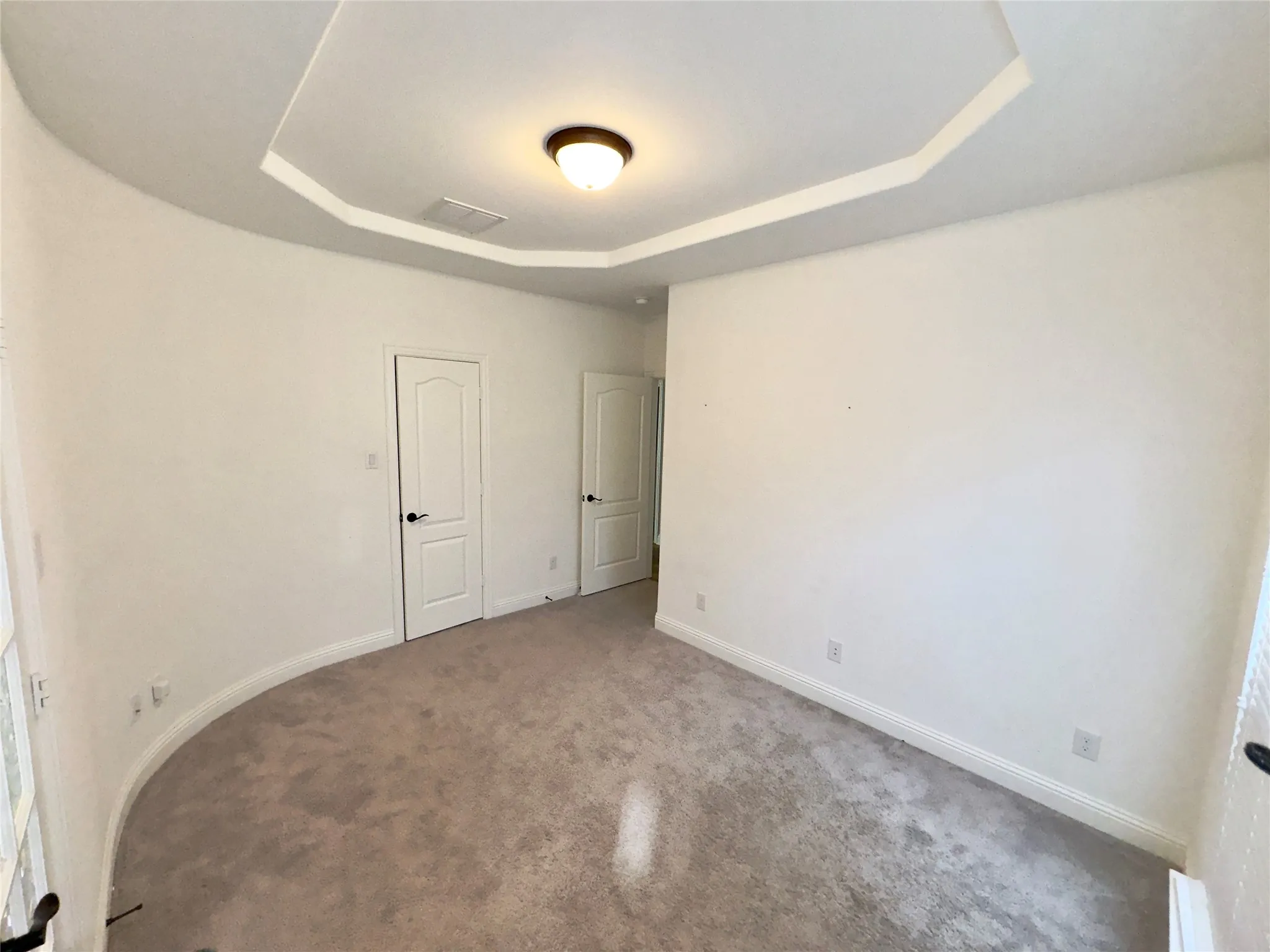 Empty room featuring carpet floors and a tray ceiling