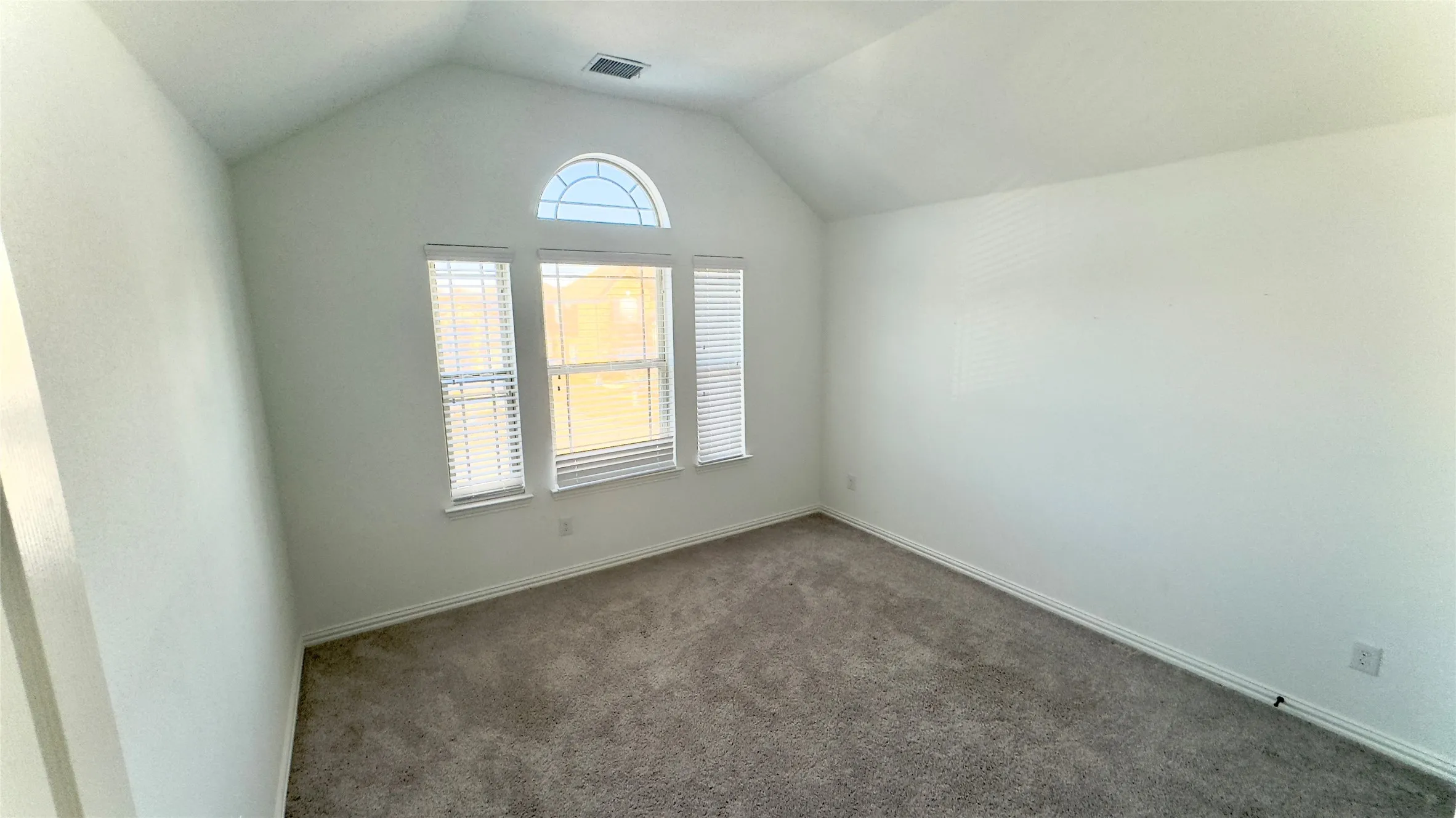 Empty room featuring lofted ceiling and dark carpet