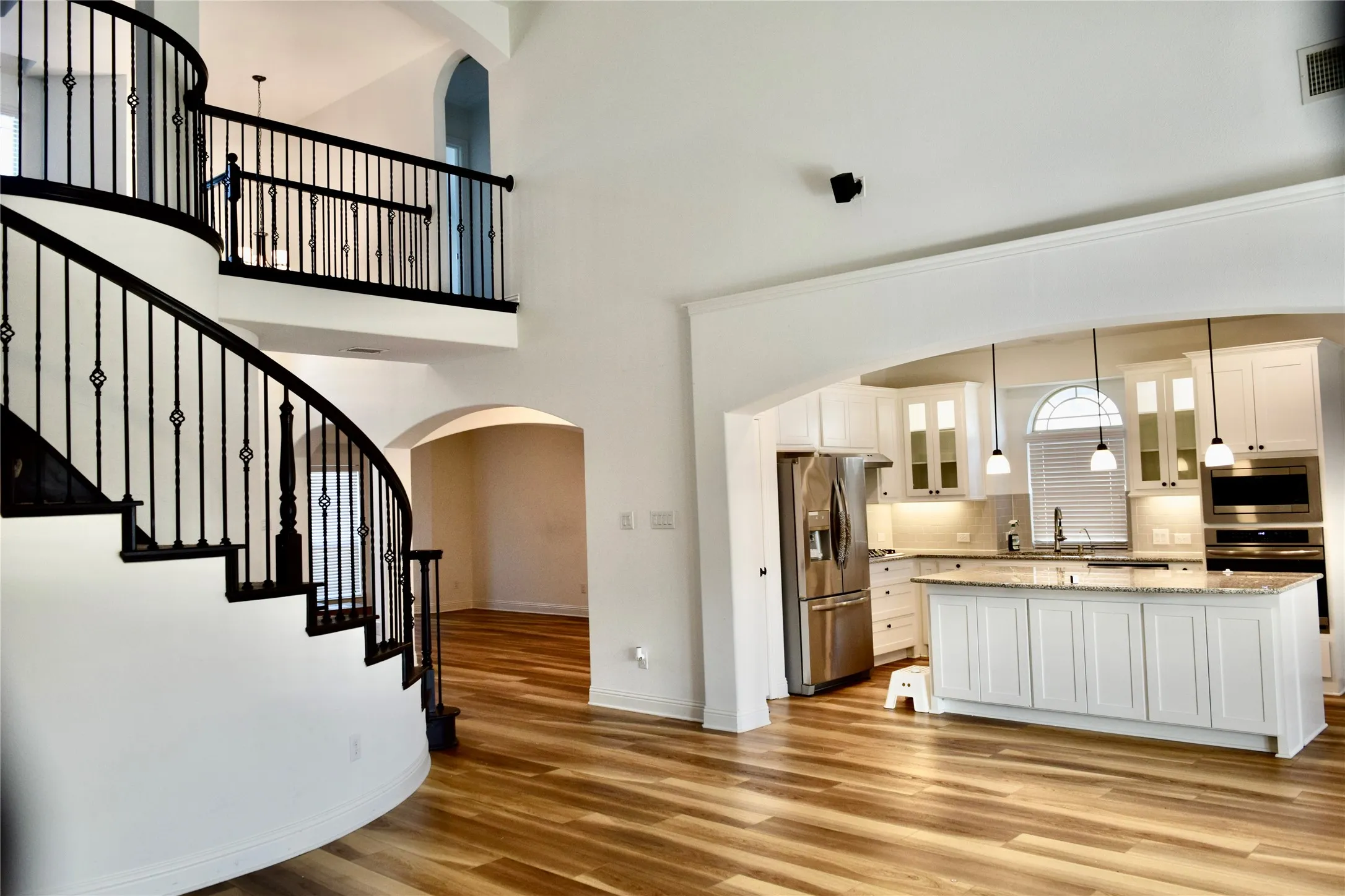 Kitchen with white cabinets, a center island, decorative backsplash, pendant lighting, and appliances with stainless steel finishes