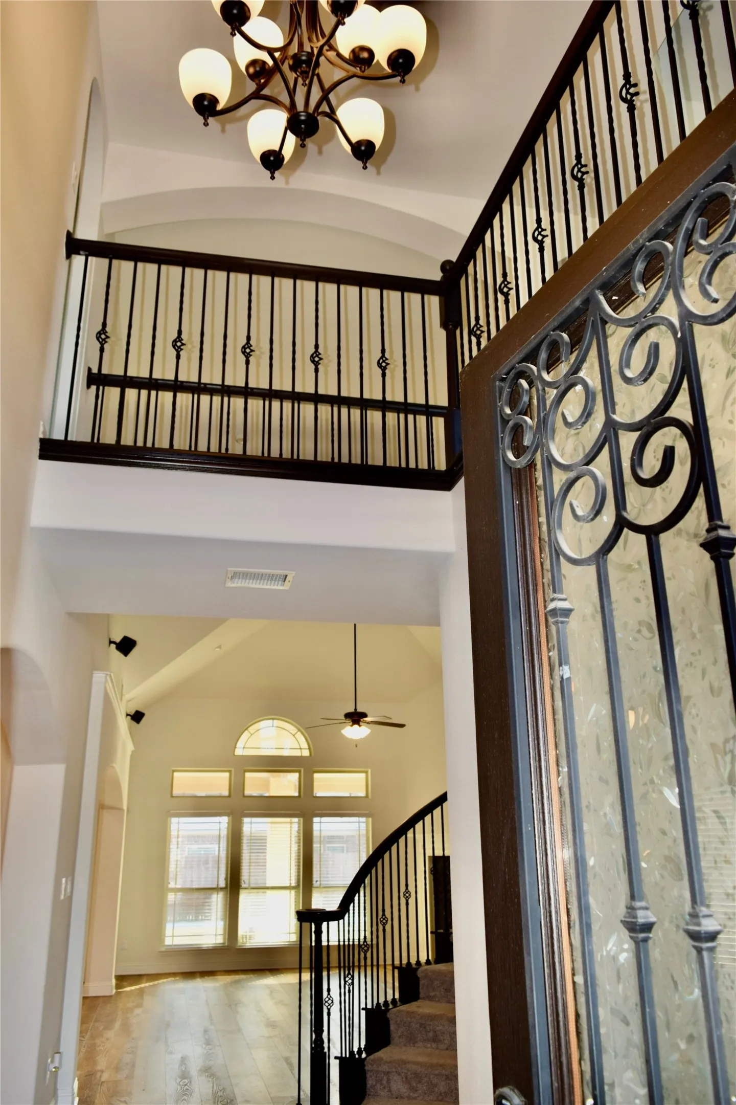 Stairs featuring ceiling fan with notable chandelier and wood-type flooring