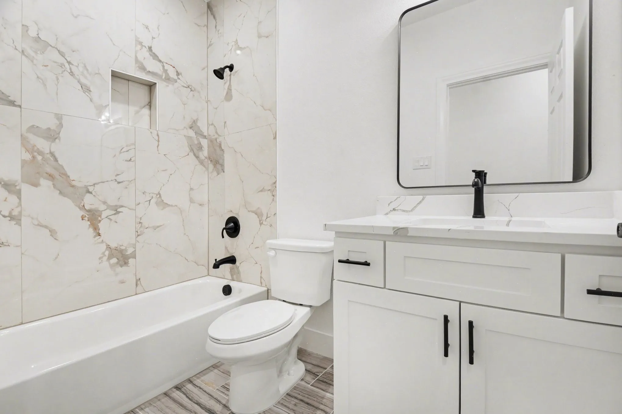 White vanity with black hardware, integrated sink, and black wall-mounted faucet