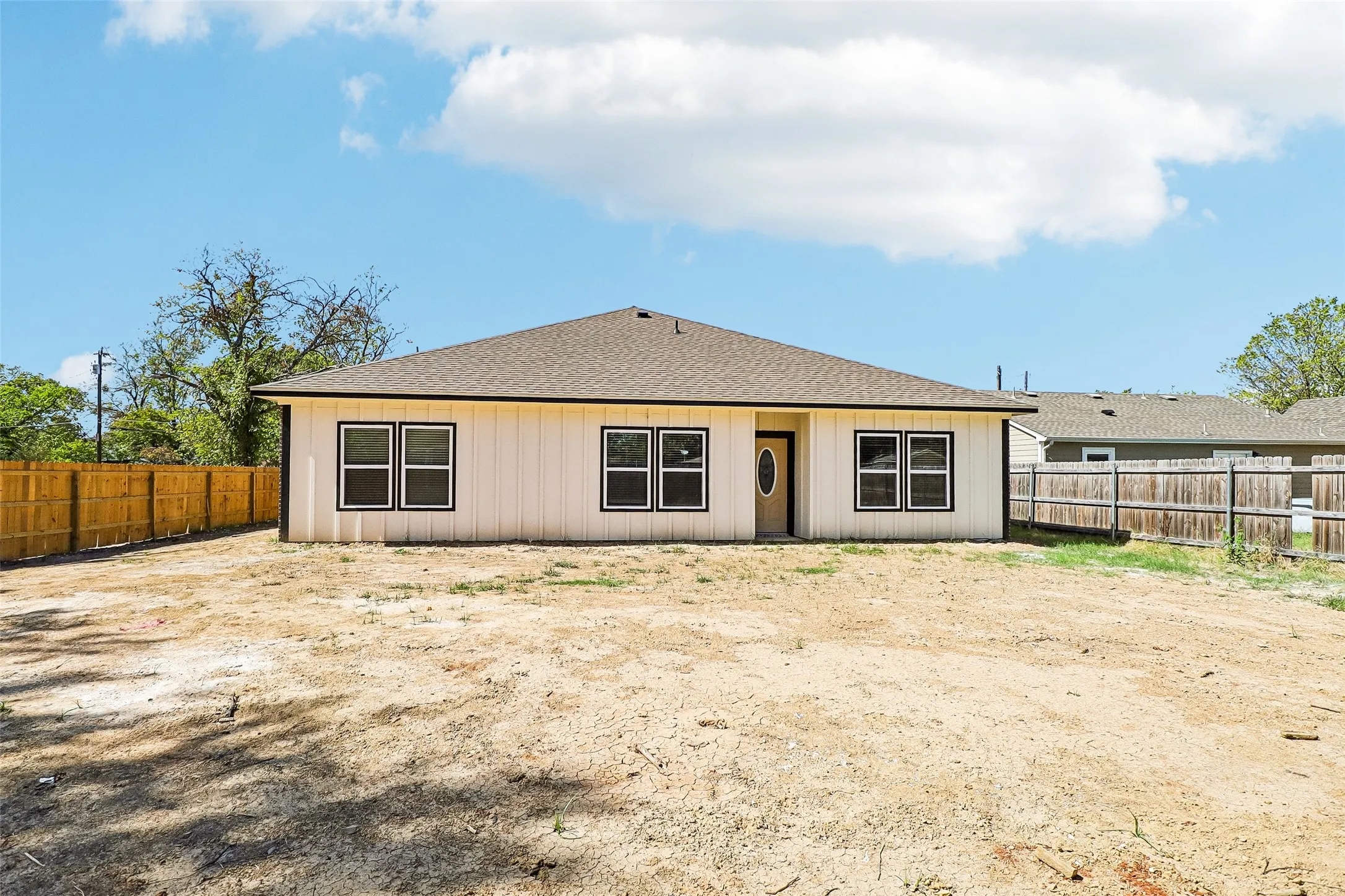 Rear exterior featuring a privacy fence, multiple windows, and a partially glass-paneled door