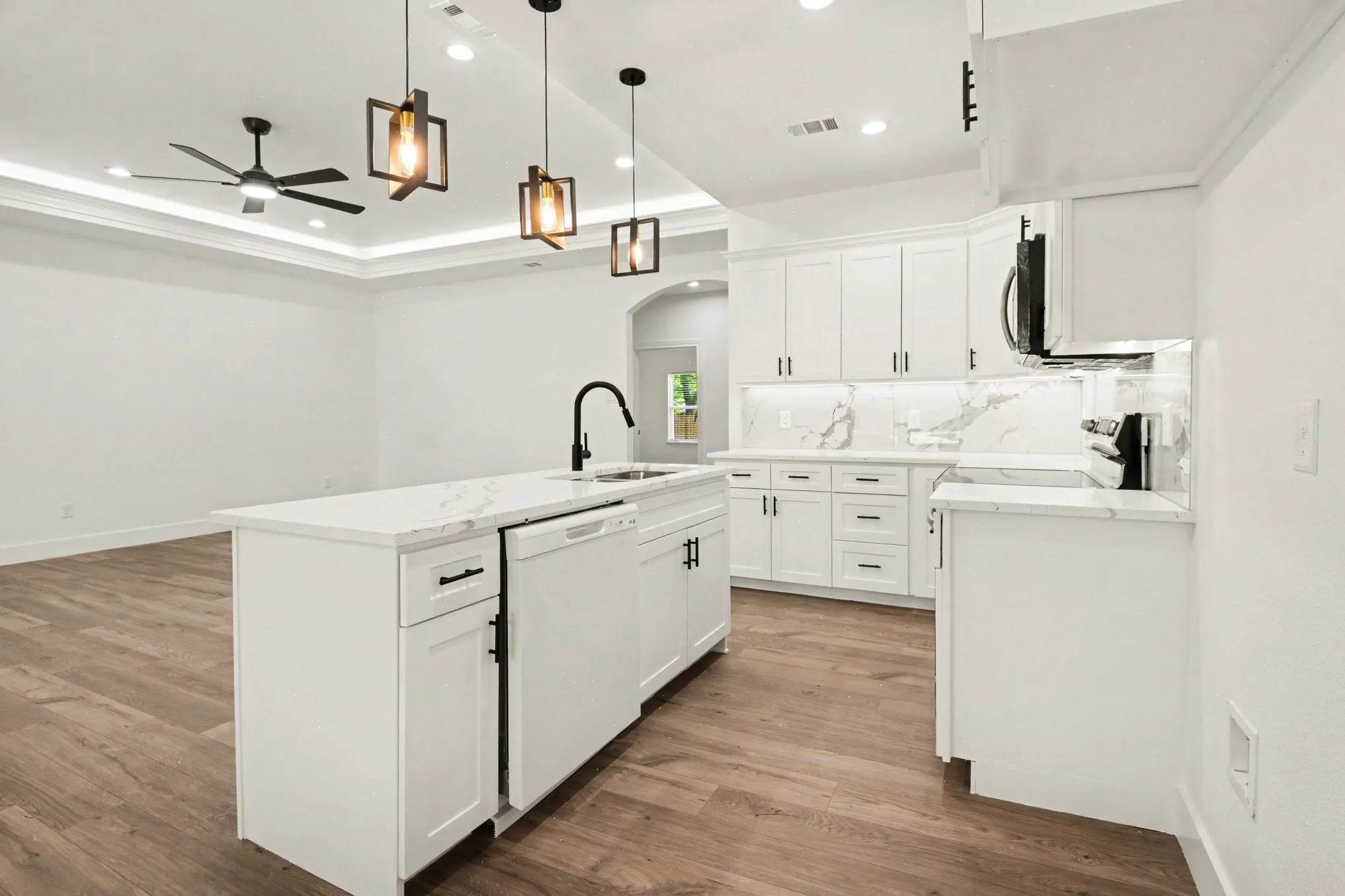 Open-concept kitchen with white cabinetry and an island featuring a built-in sink and dishwasher