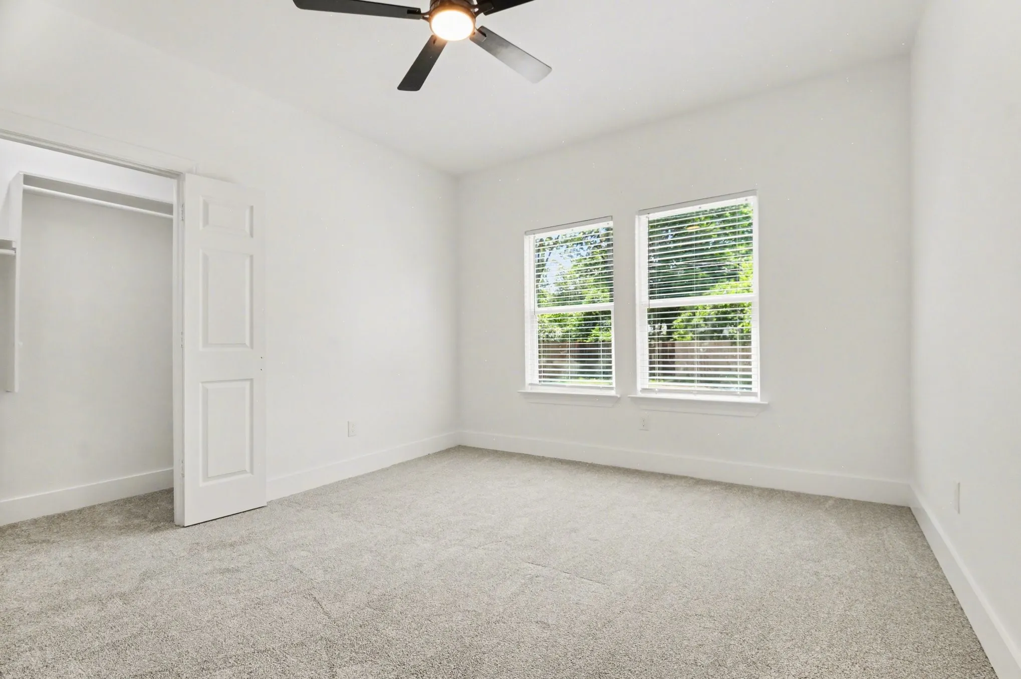 Light gray carpeting, white walls, and a ceiling fan with integrated lighting
