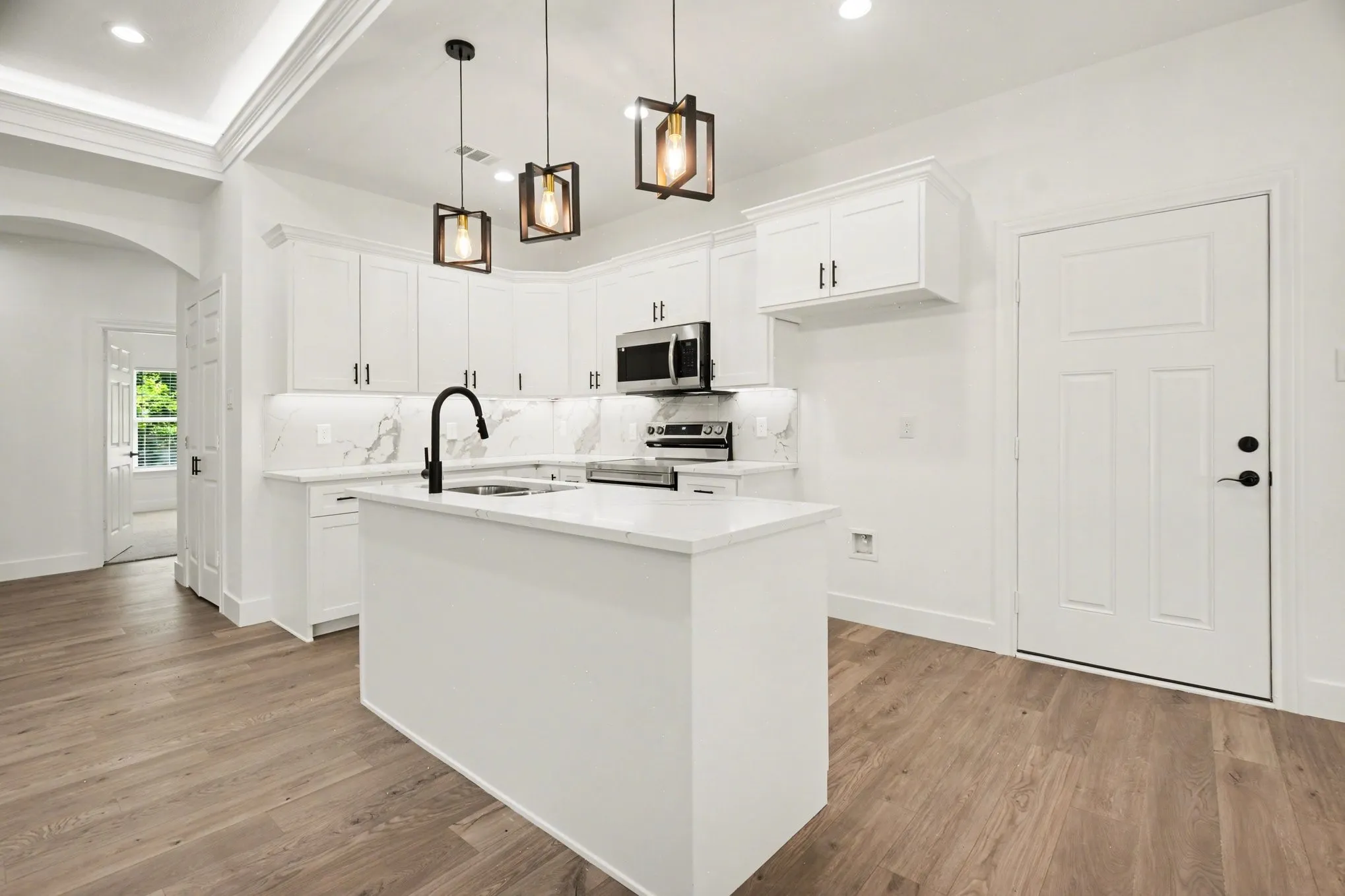 Kitchen featuring white cabinetry, wood-finish flooring, a central island, stainless steel appliances, and statement pendant lighting
