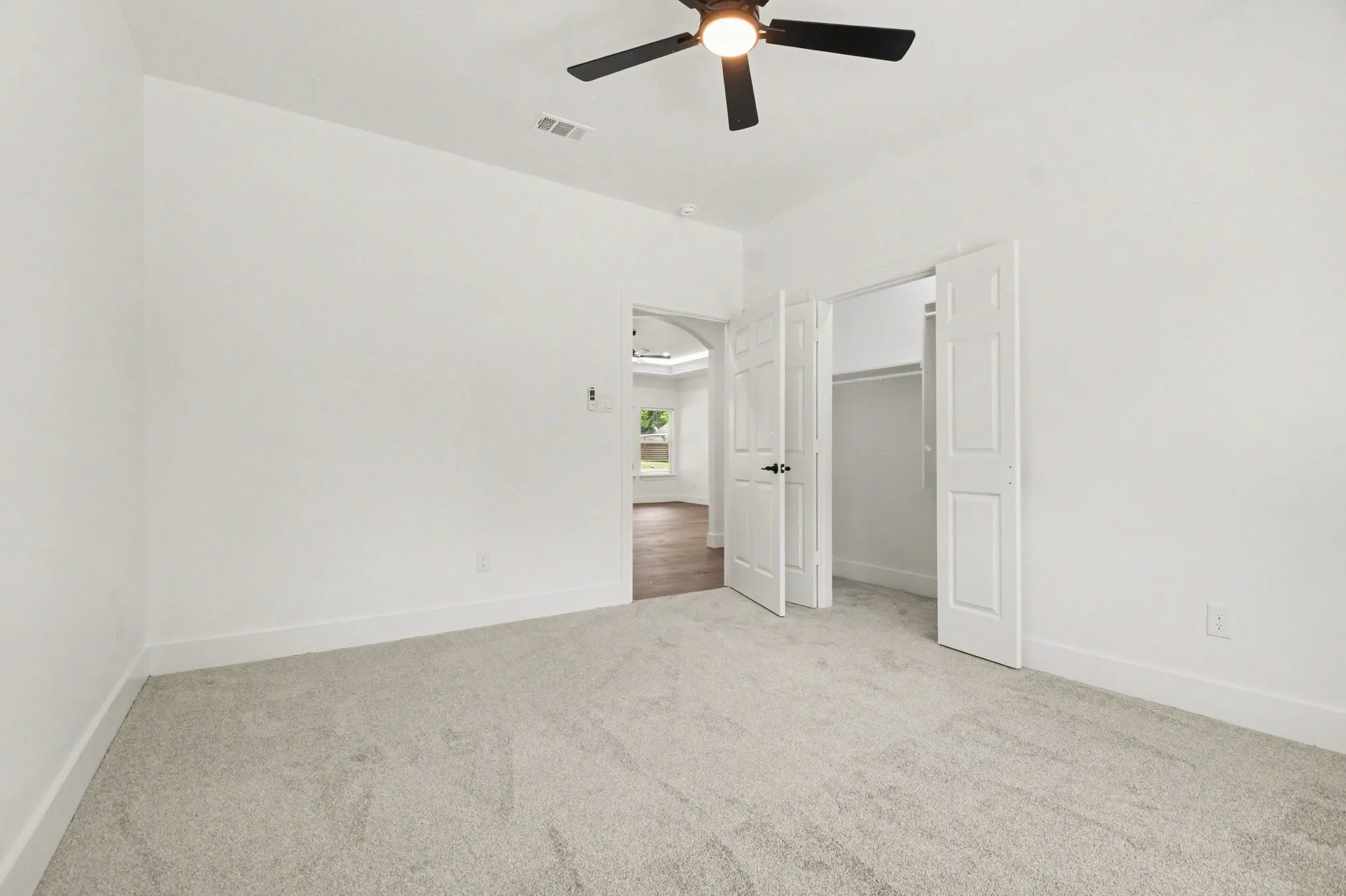 Neutral carpet flooring, crisp white walls, ceiling fan with integrated lighting, and a closet with bifold doors