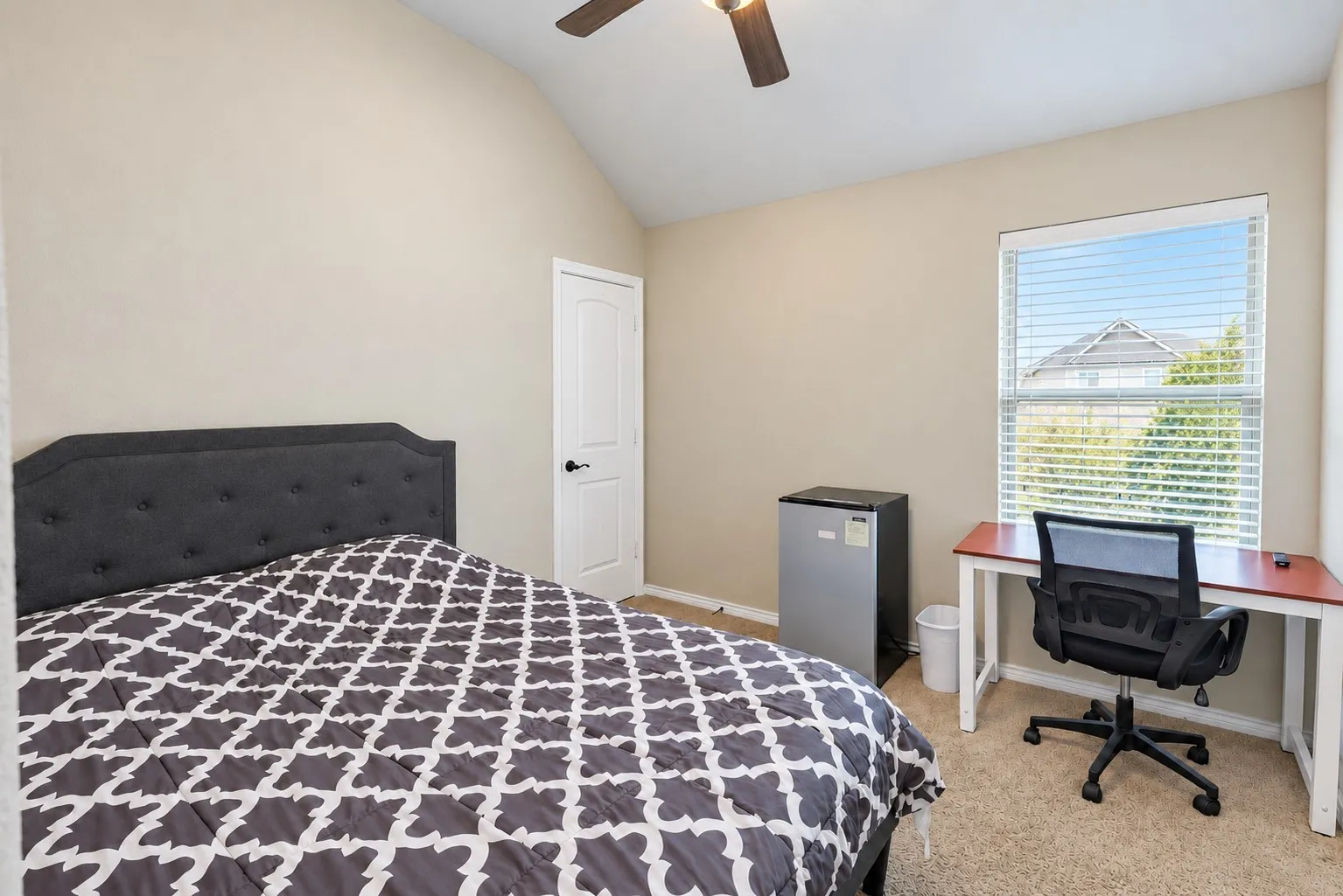Vaulted ceiling, ceiling fan, single window with blinds, carpeted flooring, and a solid core door