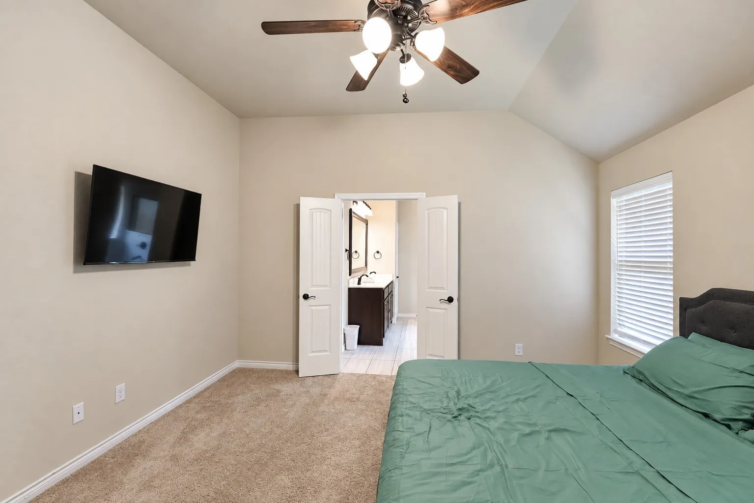 Vaulted ceiling with a ceiling fan, carpeted flooring, and a window with blinds