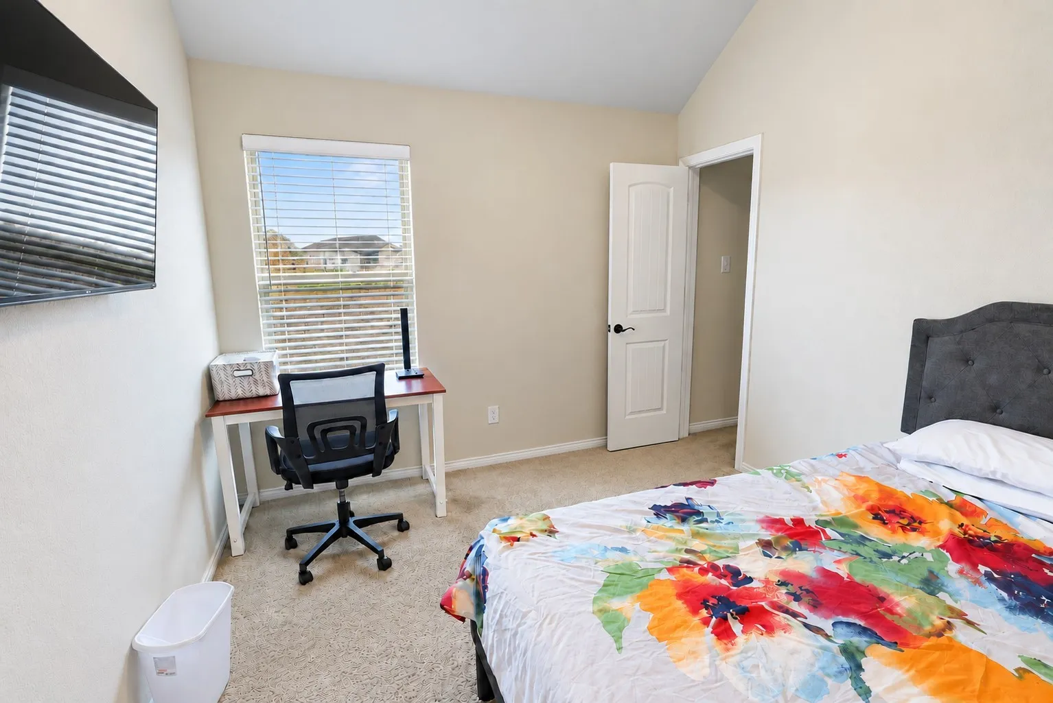 Carpeted flooring, vaulted ceiling, single window with blinds, and a white interior door