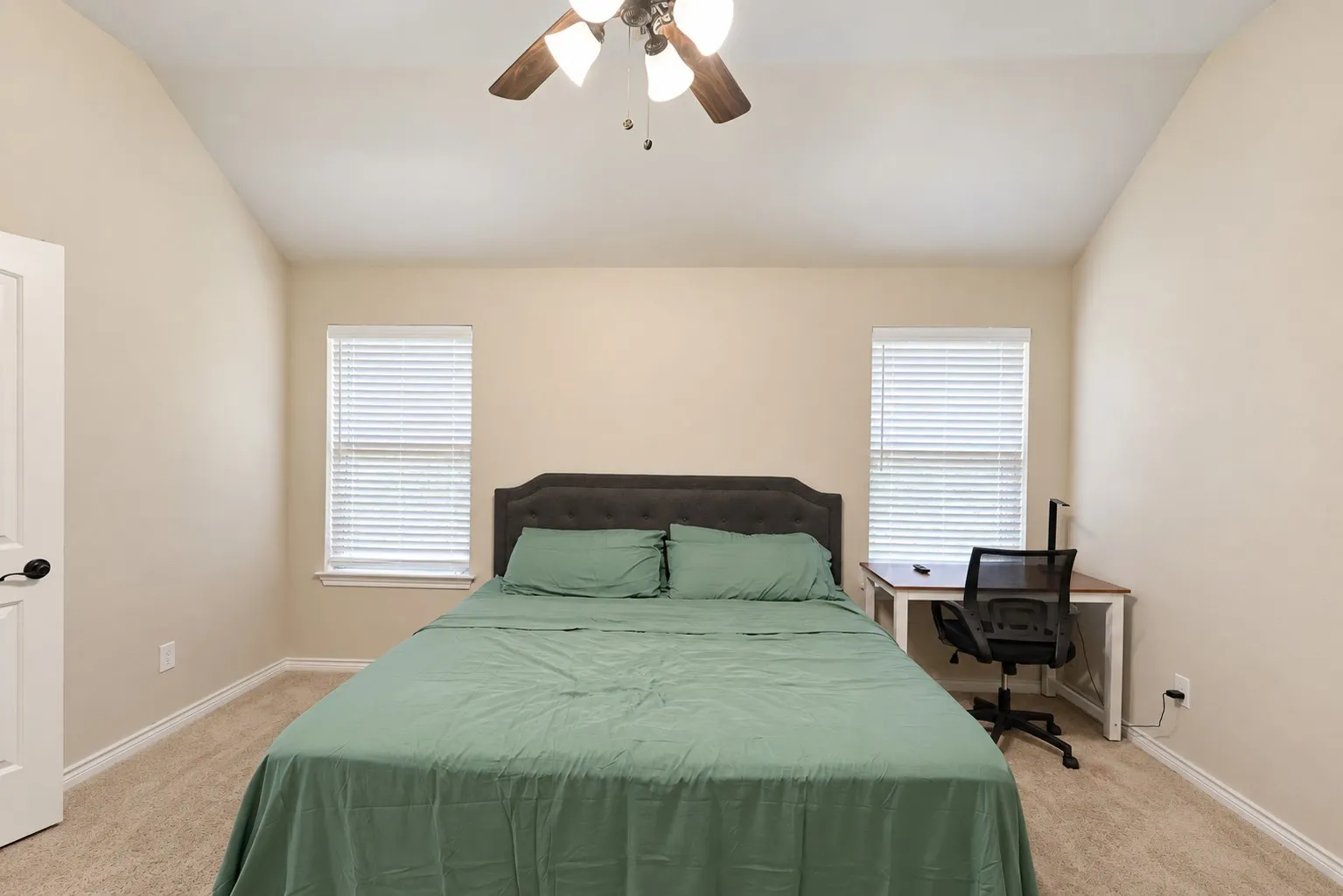 Vaulted ceiling with a ceiling fan, carpet flooring, and two windows with blinds