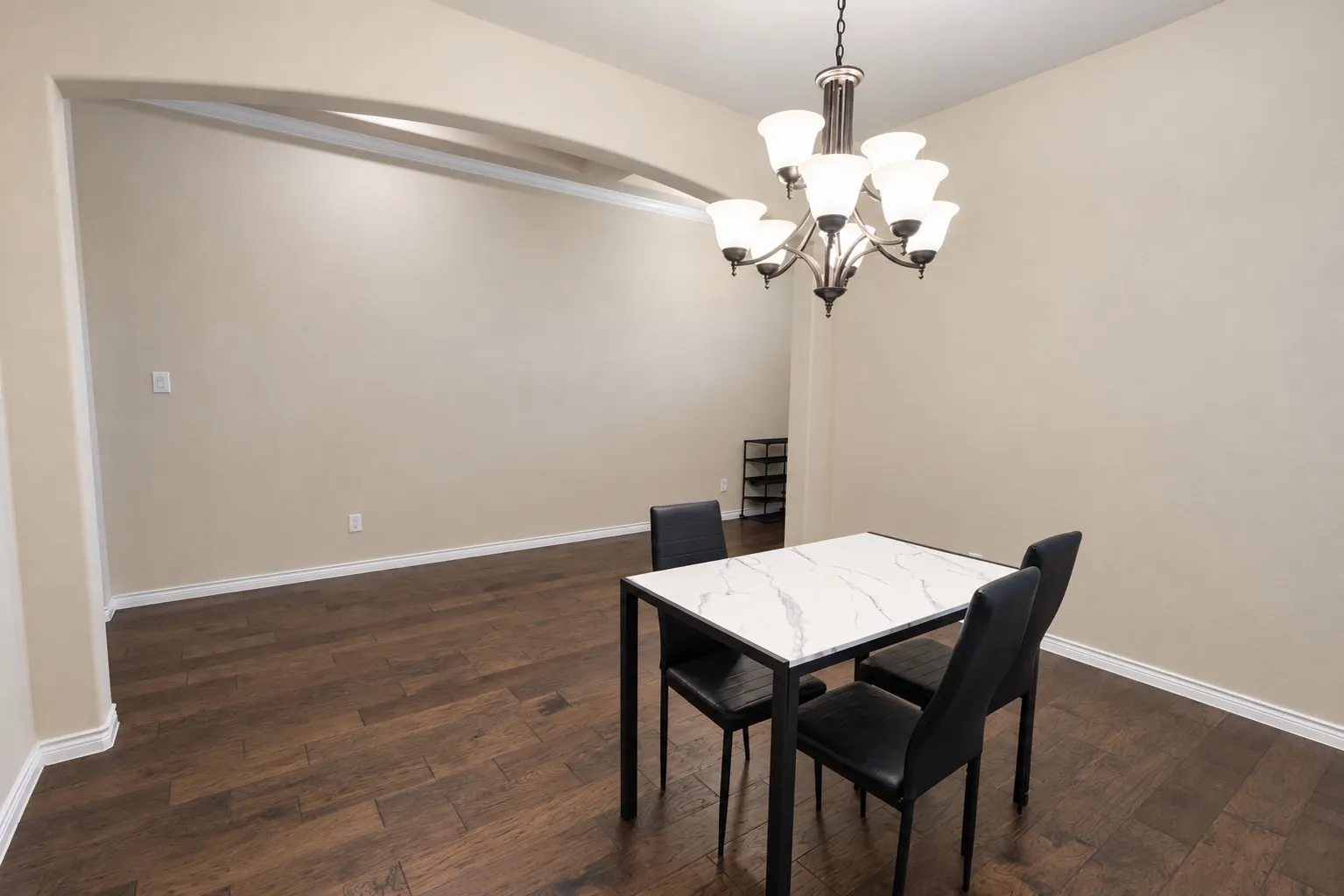 Wood-finish flooring, recessed archway, and a multi-light chandelier