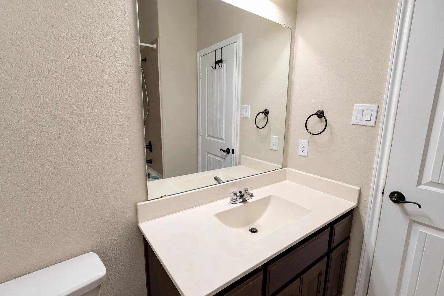 Vanity with an integrated sink, polished chrome faucet, and a large mirror