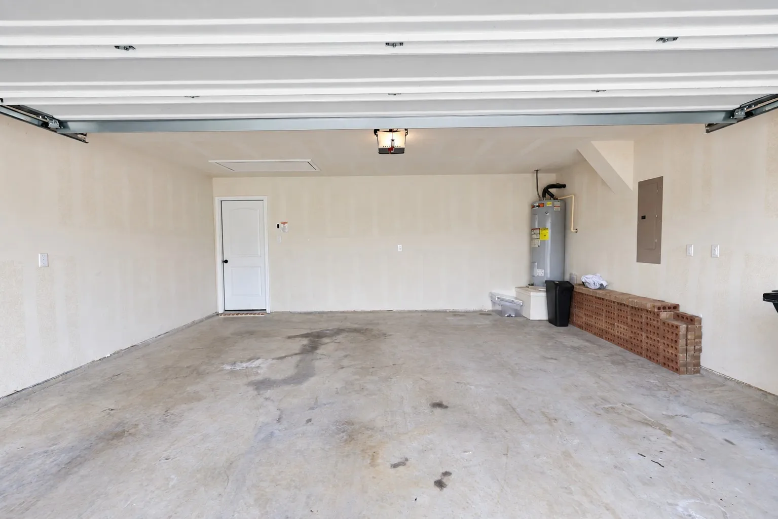 Spacious garage with concrete flooring, overhead garage door rails, and a ceiling-mounted light fixture