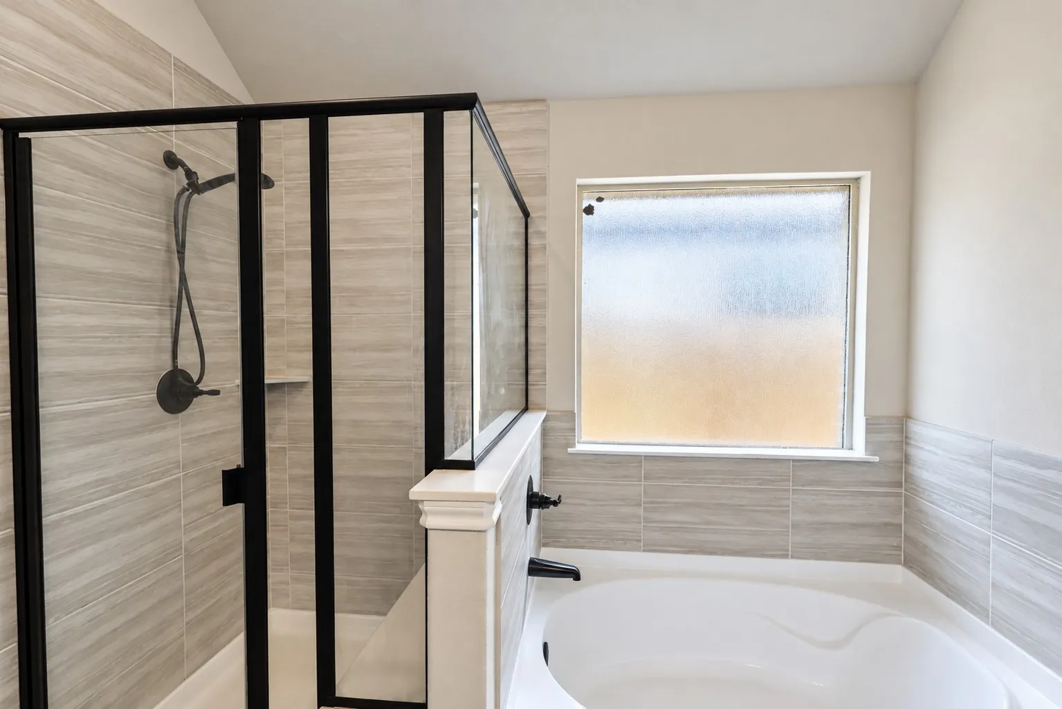 Walk-in shower with matte black hardware, tiled shower walls, and a built-in shower niche