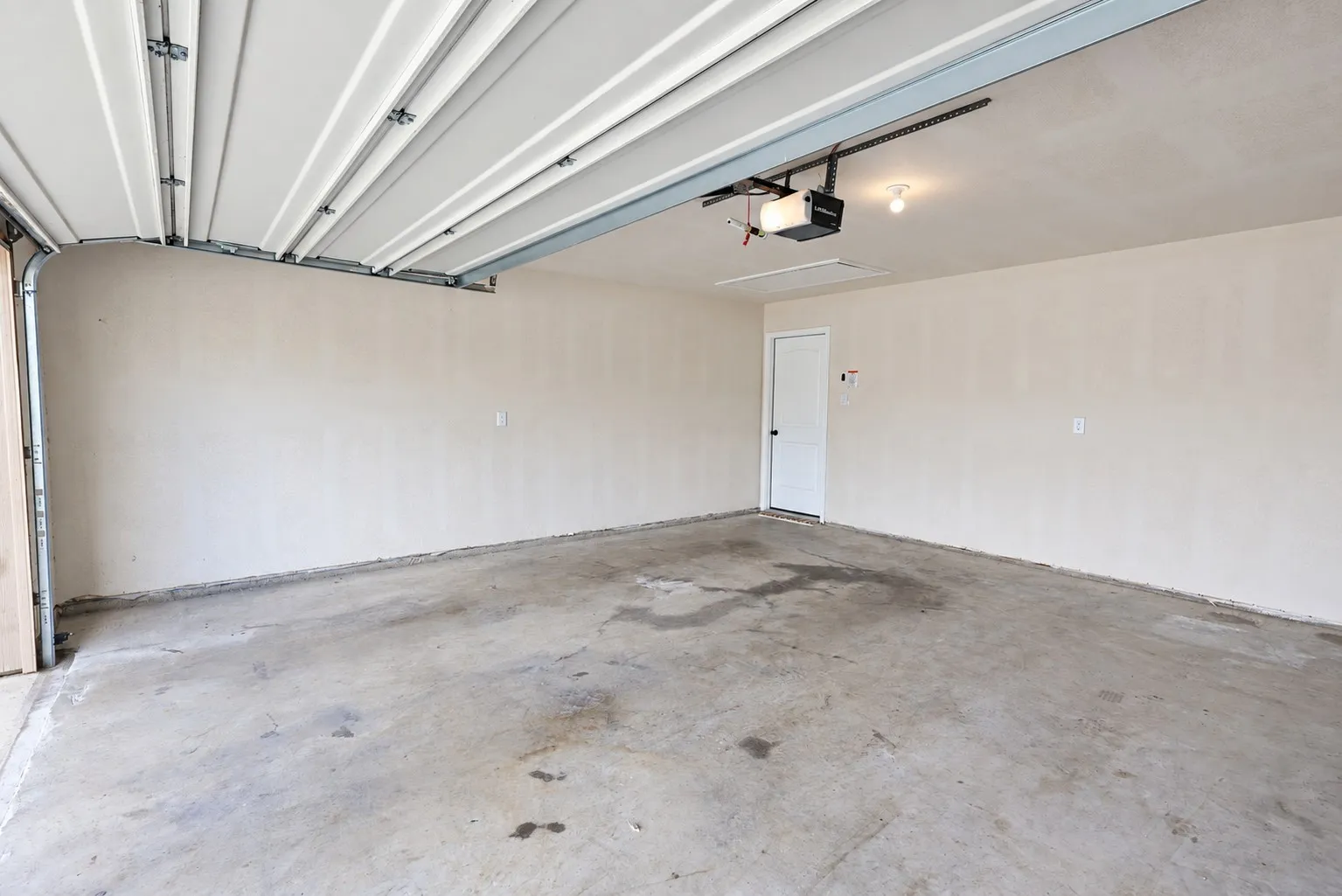 Concrete flooring, textured walls, overhead lighting, and an internal access door