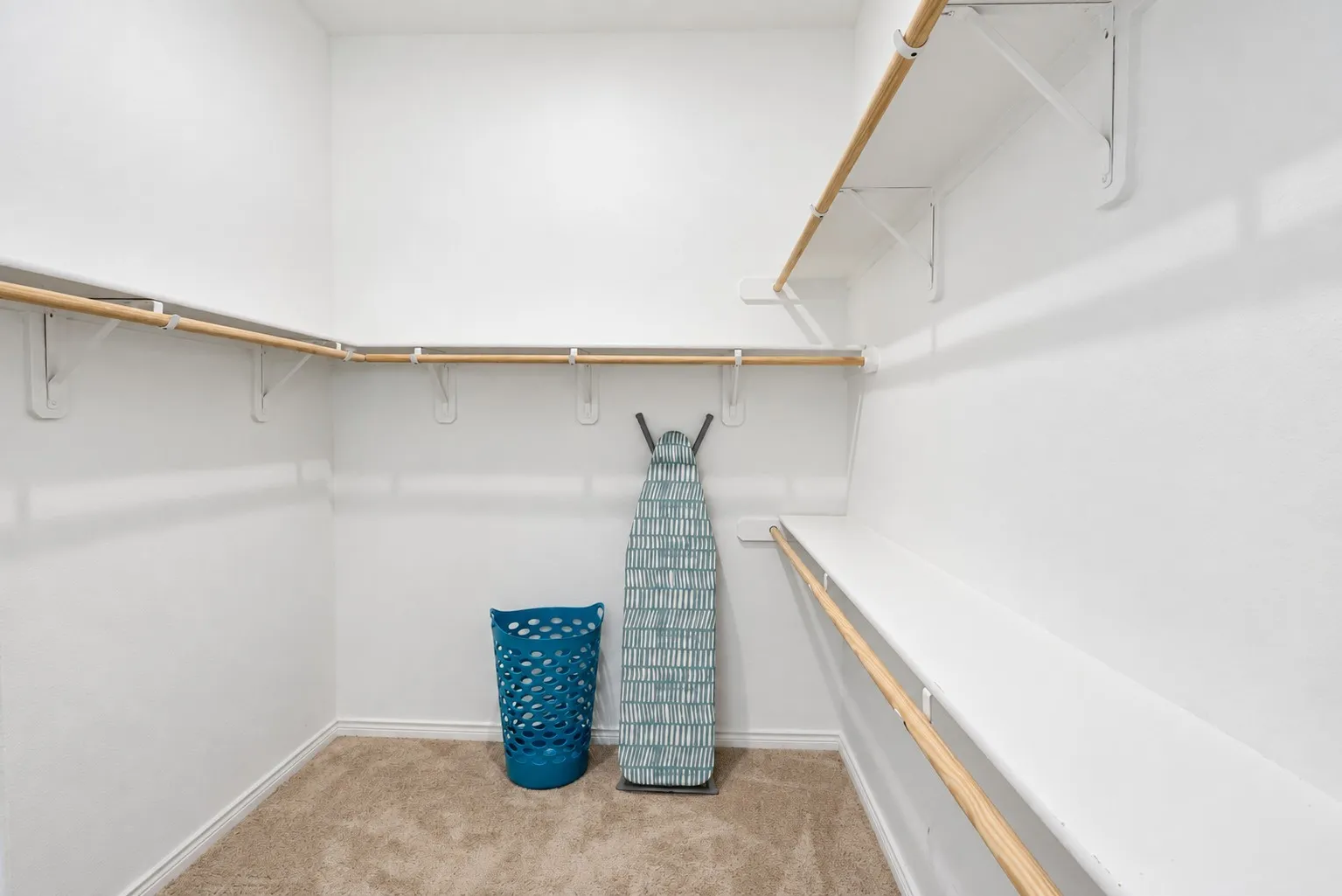Carpeted closet with multiple levels of built-in shelving and hanging rods