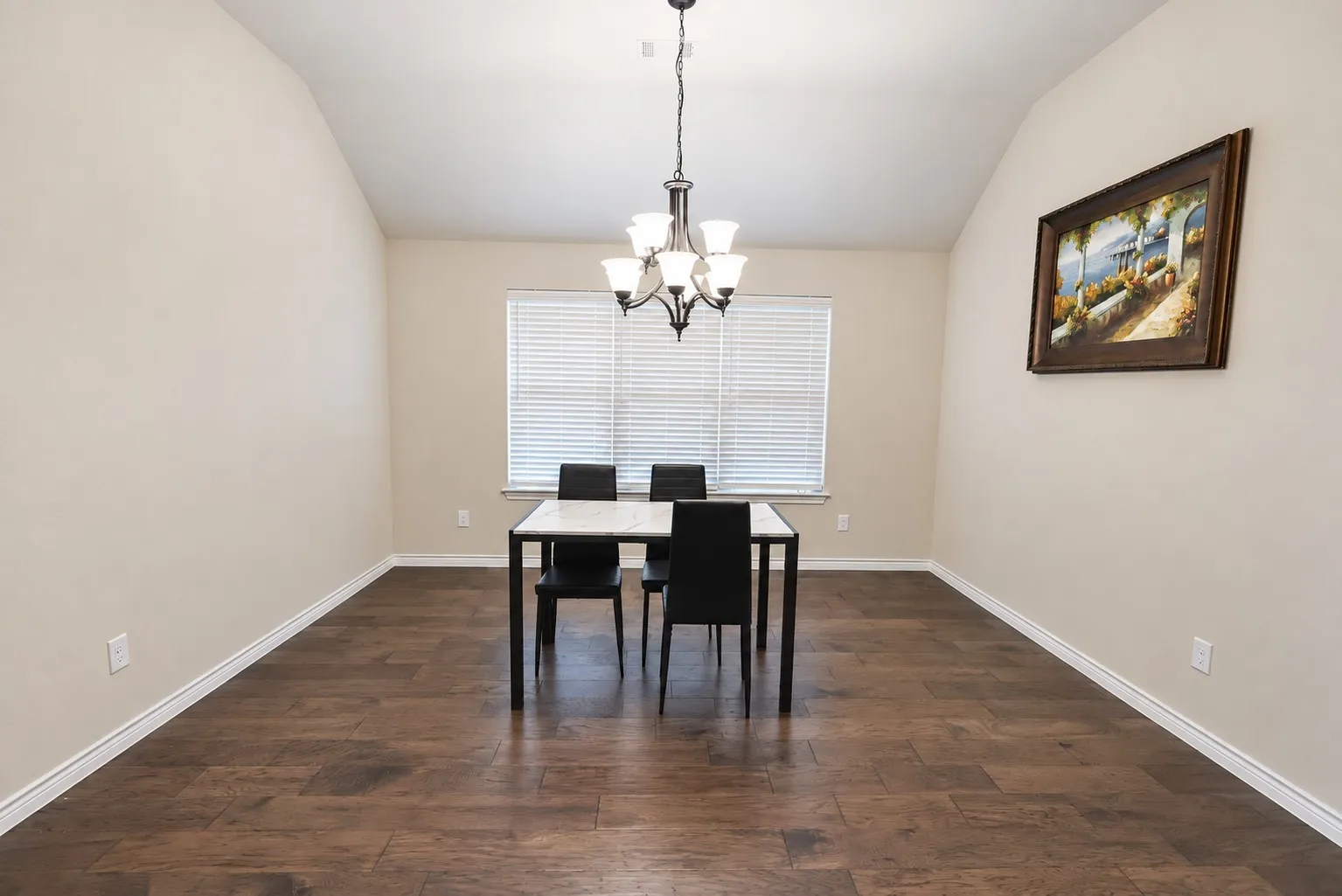 Vaulted ceiling with a chandelier, wood-finish flooring, and window with blinds