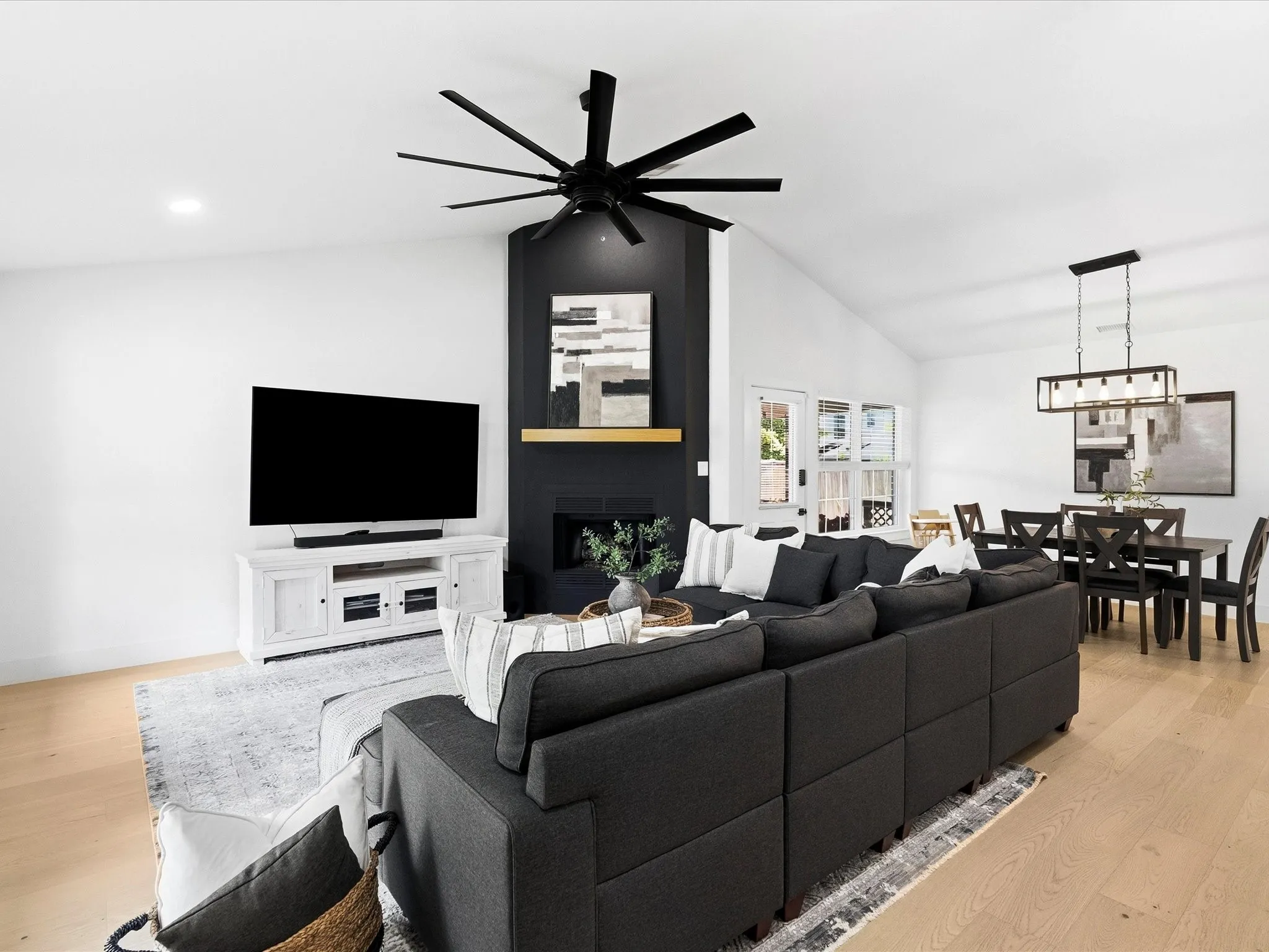 Vaulted ceiling with a contemporary ceiling fan, fireplace with a wood mantel, wood-finish flooring, and recessed lighting