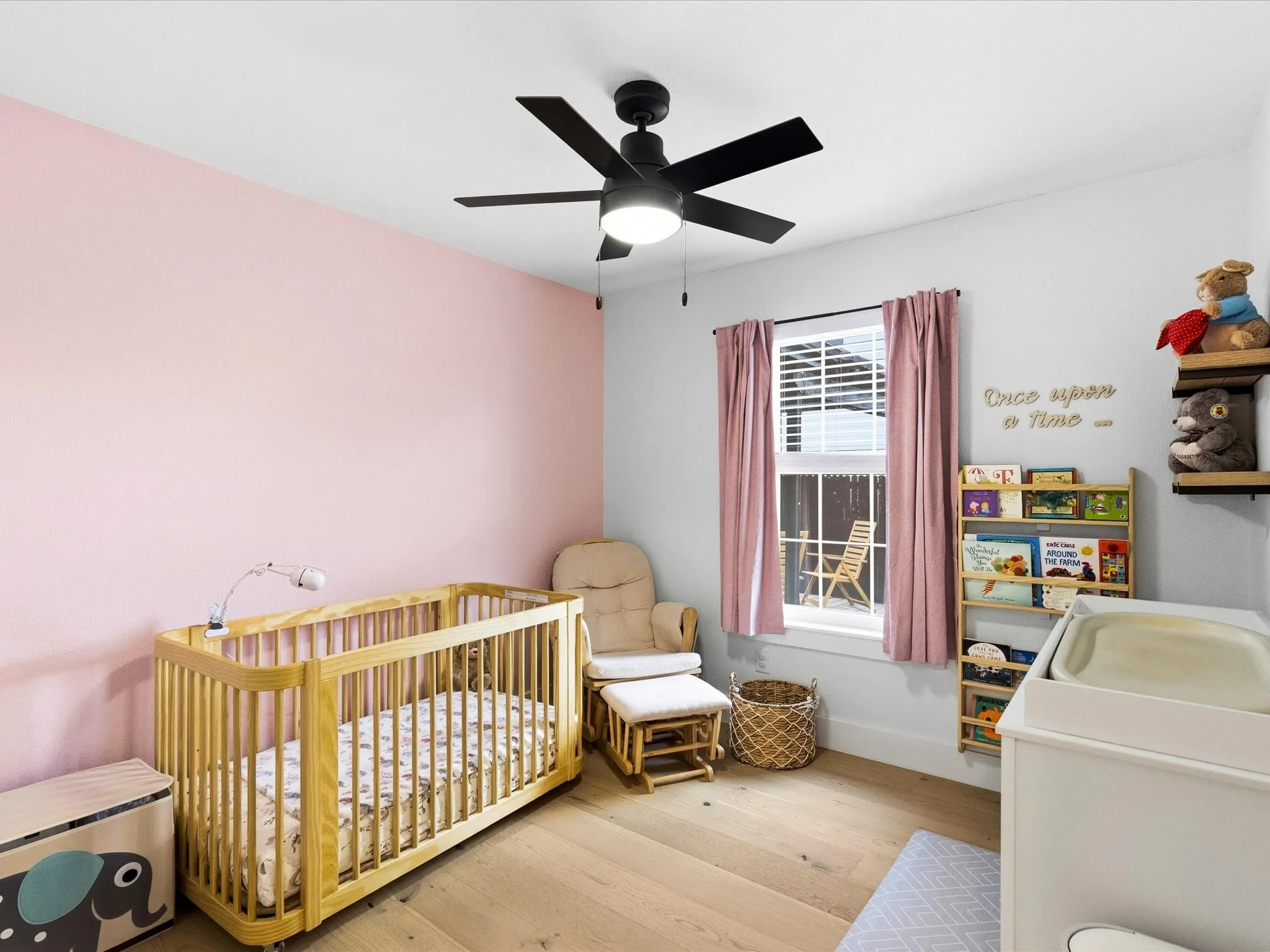 Wood-finish flooring with a ceiling fan, window, and built-in shelving