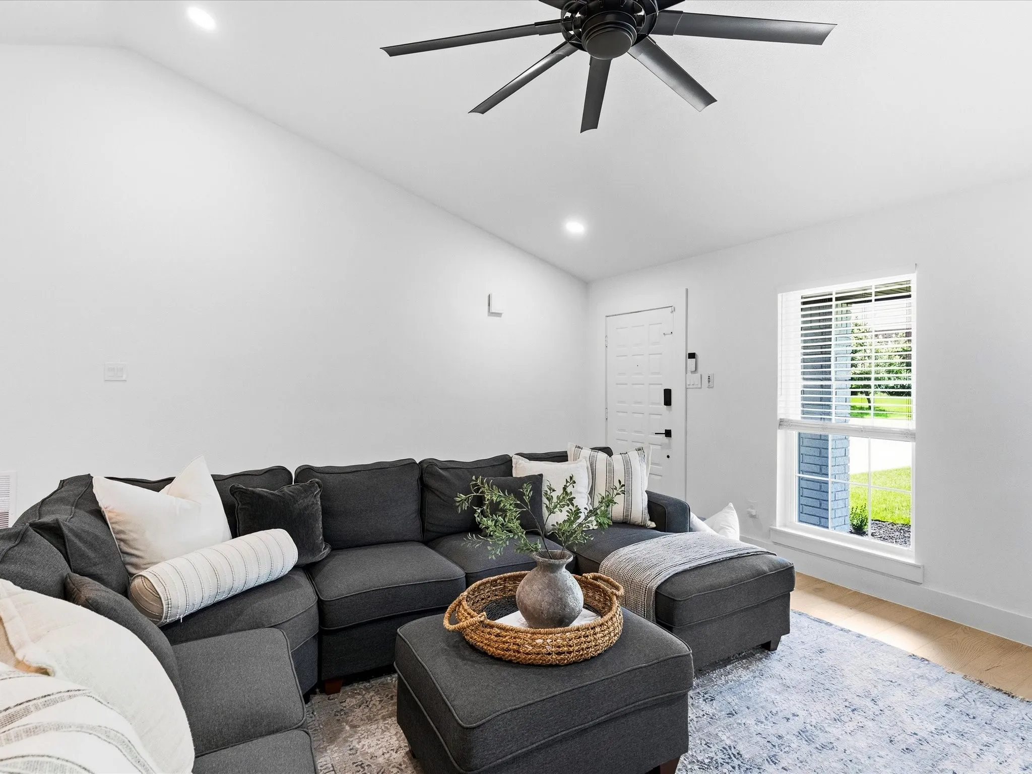 Vaulted ceiling with a ceiling fan, white paneled entry door, recessed lighting, and wood-finish flooring