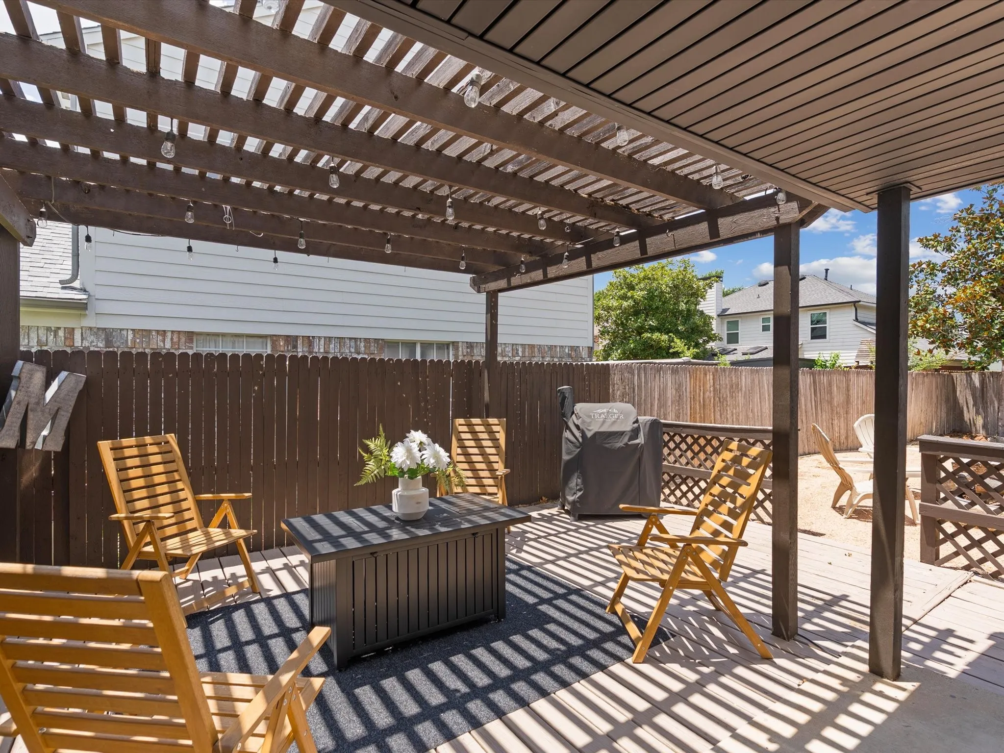 Expansive outdoor patio featuring a slatted pergola, durable wood fencing, and a built-in privacy screen