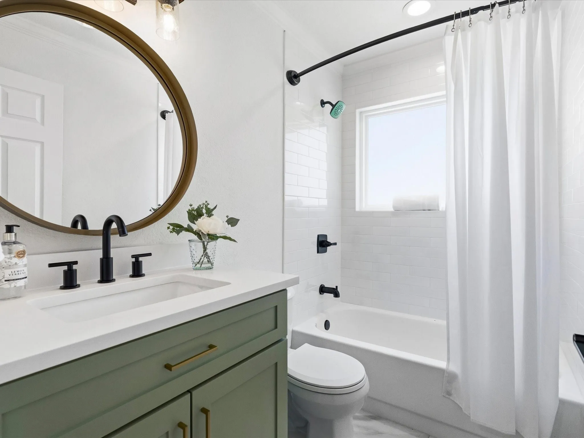 Green vanity with brass hardware, white countertop, and matte black faucet