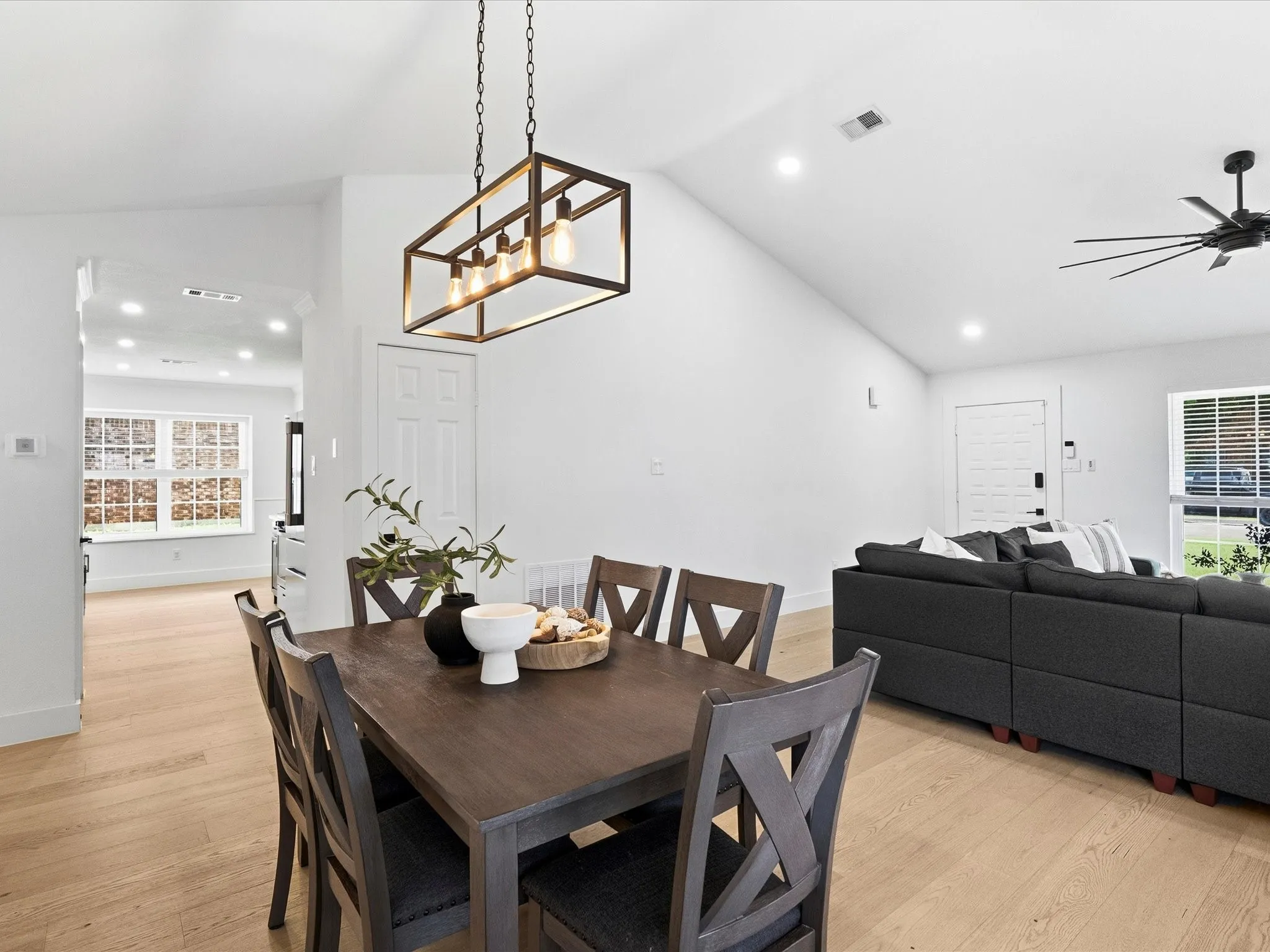 Vaulted ceiling with recessed lighting, wood-finish flooring, and a modern linear chandelier