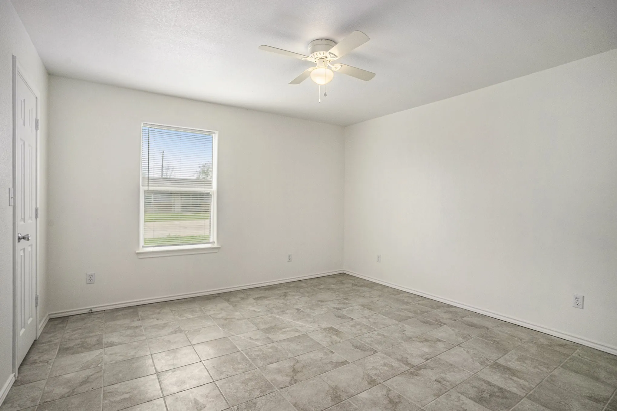 Room featuring light-toned tile flooring, a window with white trim, and a ceiling fan with integrated lighting