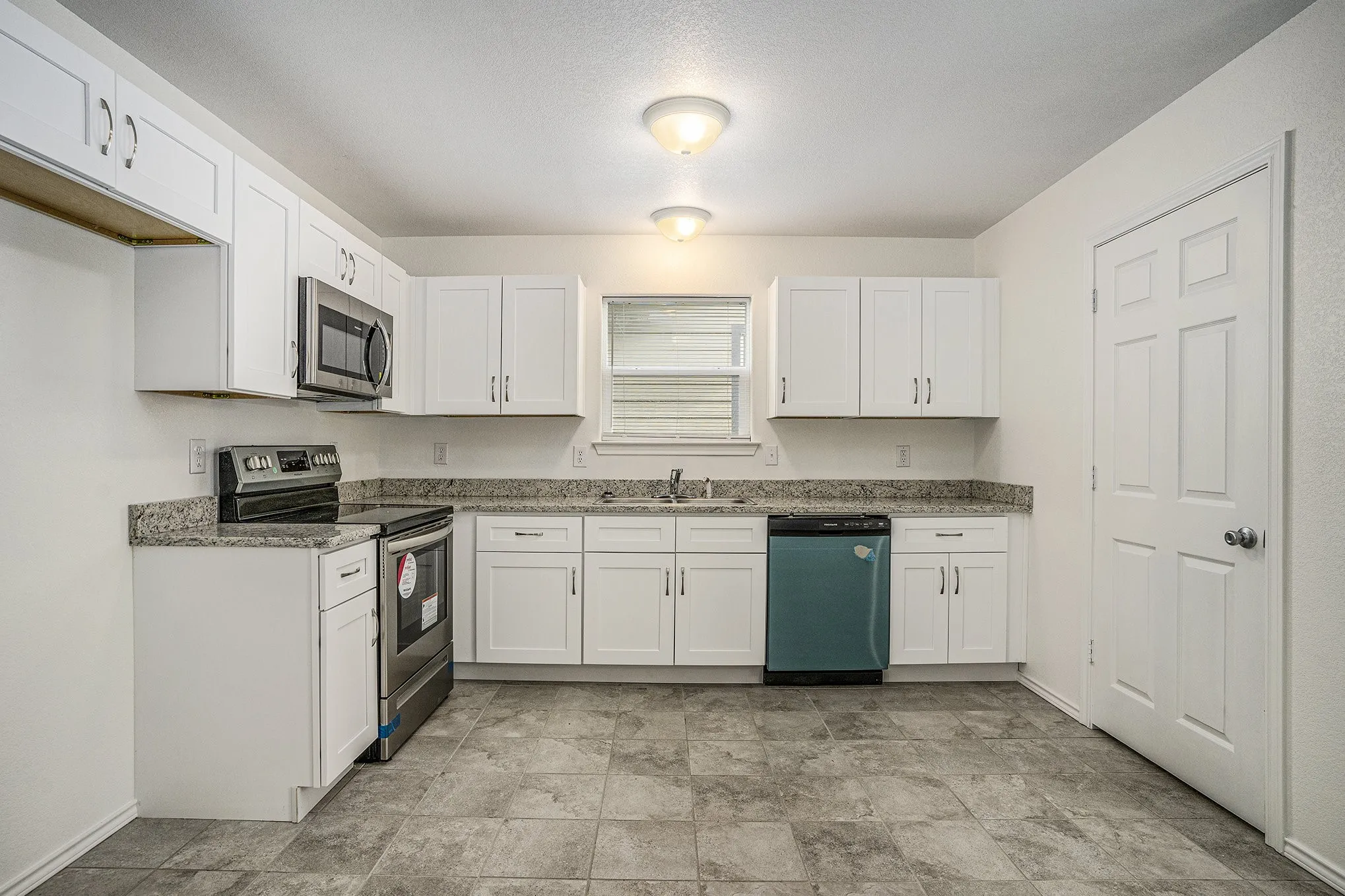 Kitchen featuring white cabinetry, stone-finish countertops, stainless steel appliances, and tile flooring