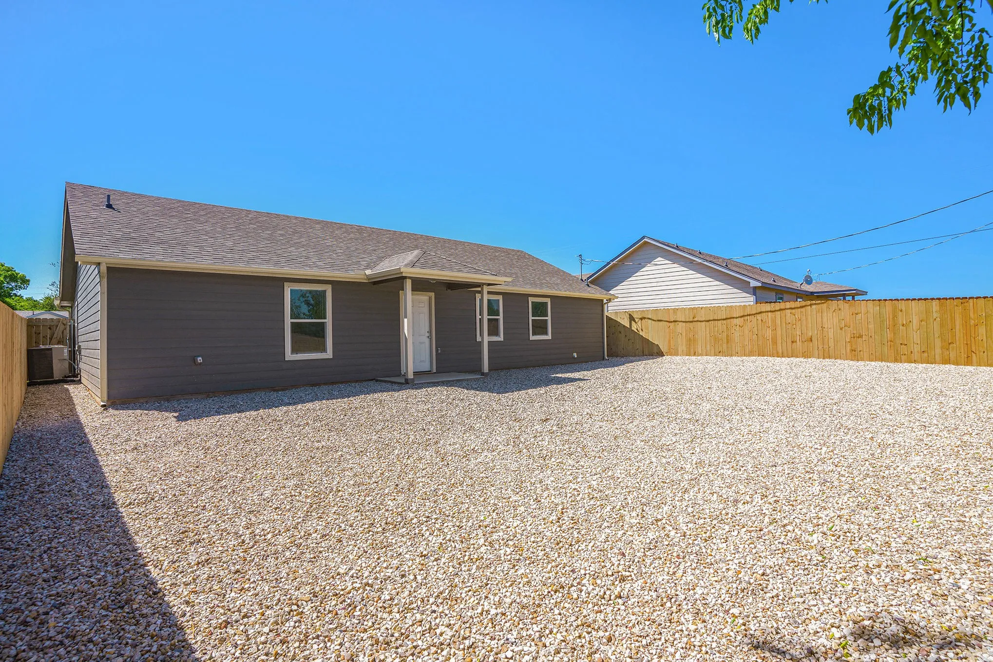 Exterior featuring dark gray horizontal siding, a light gray asphalt shingle roof, white trim accents, and a full wood privacy fence