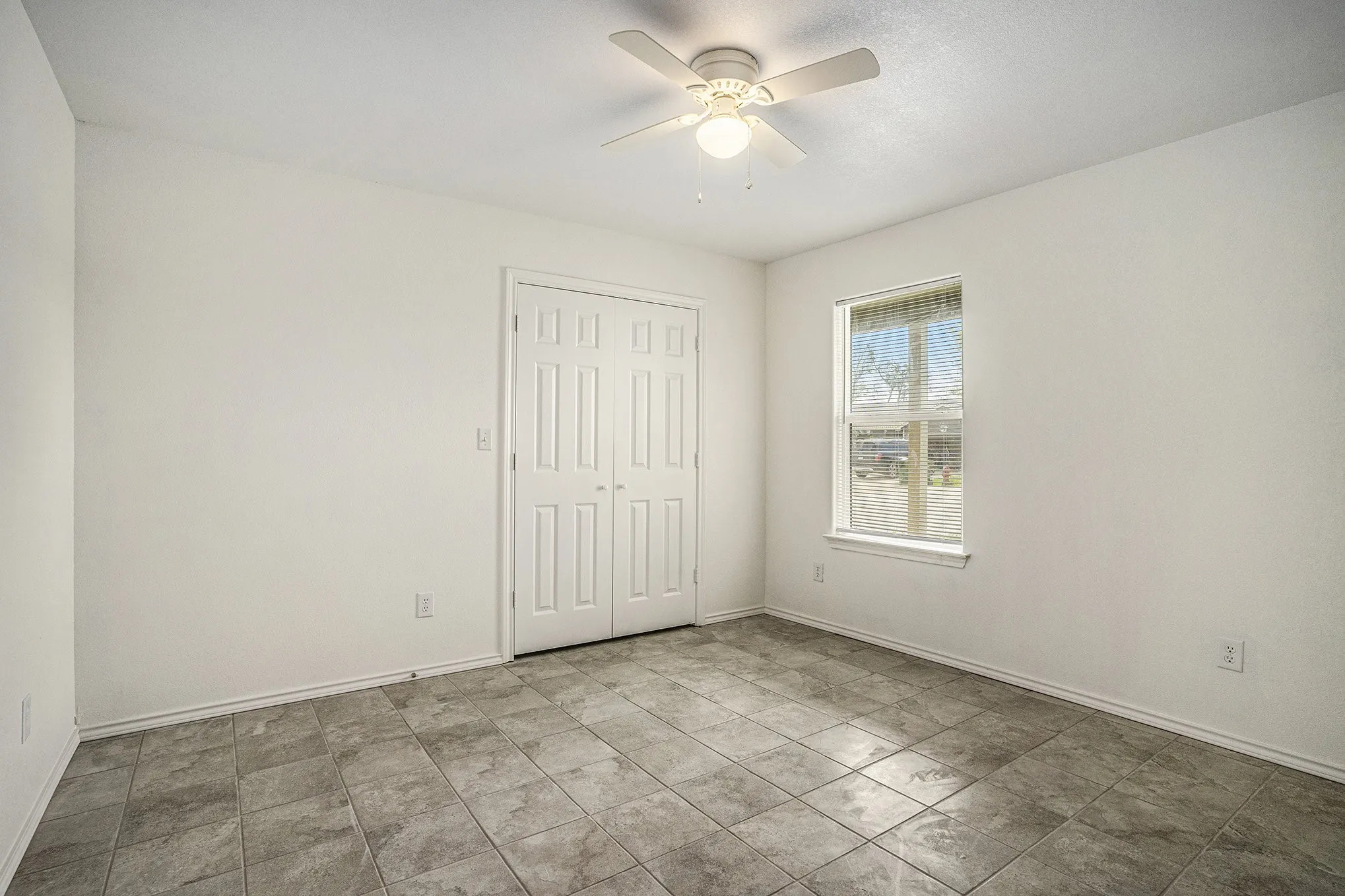 Ceramic tile flooring, bright white walls, double-door closet, and ceiling fan with integrated lighting
