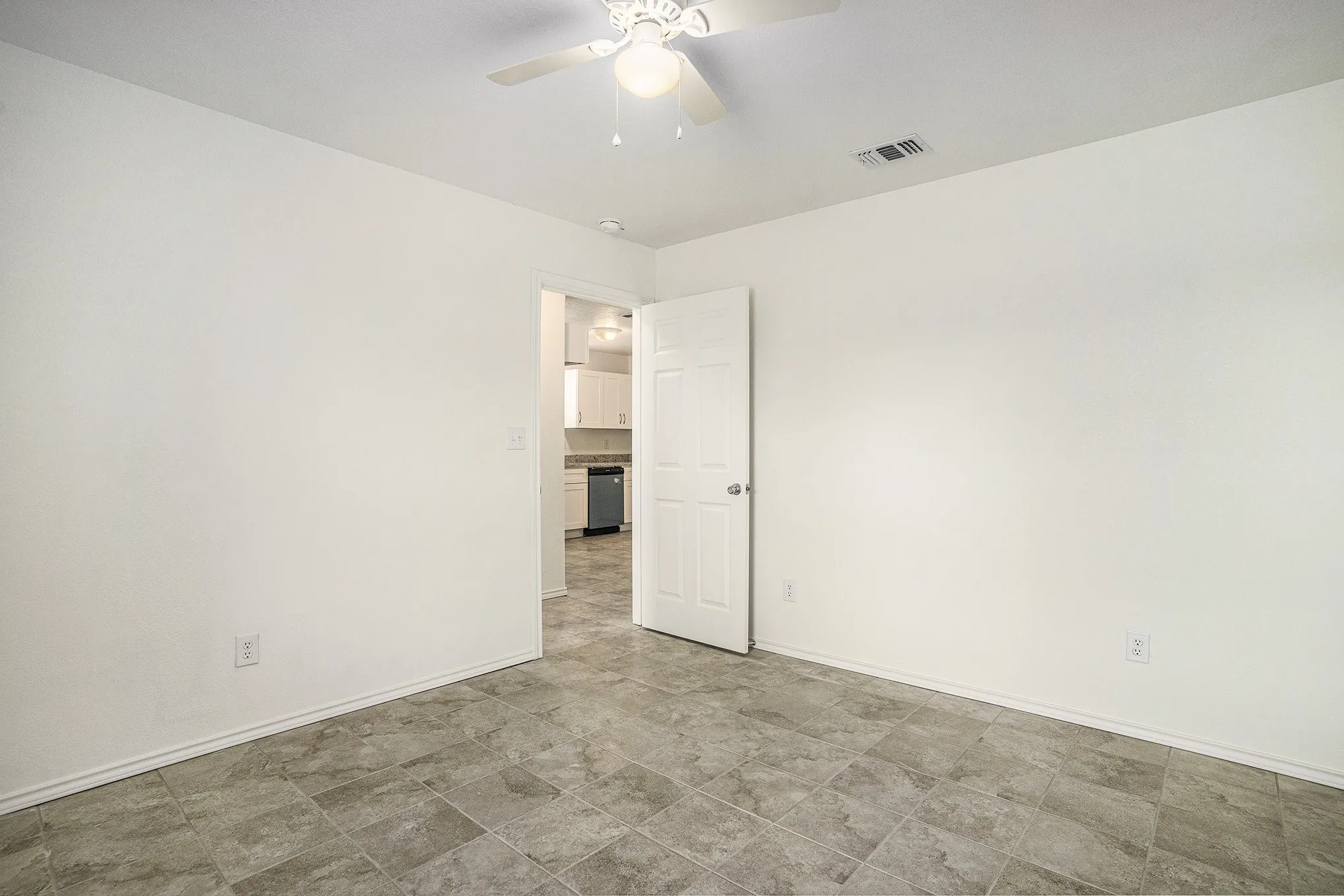 Neutral-toned tile flooring, white walls, and a ceiling fan with integrated lighting