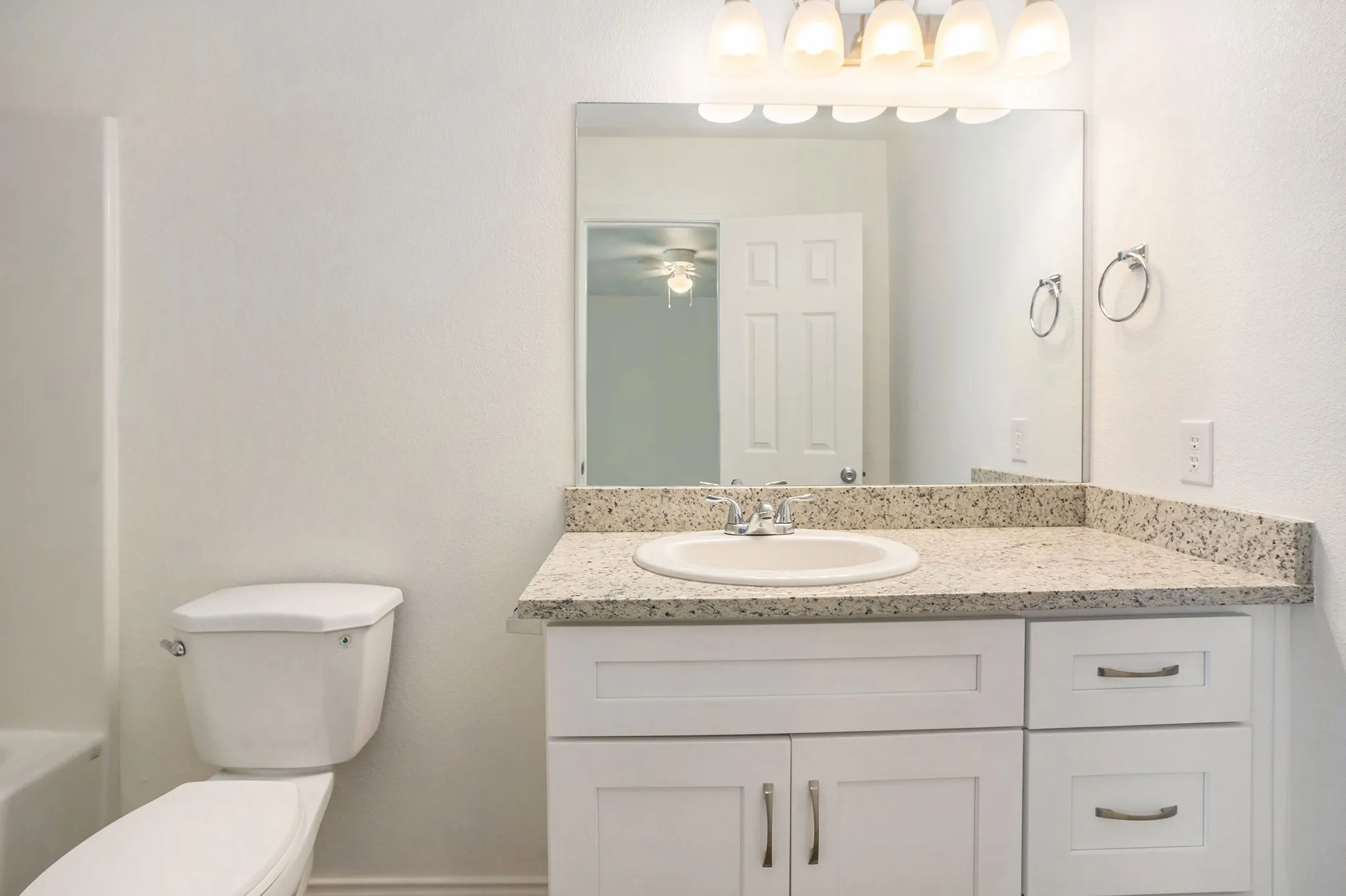 Vanity with a light-colored countertop, integrated sink, and white cabinetry