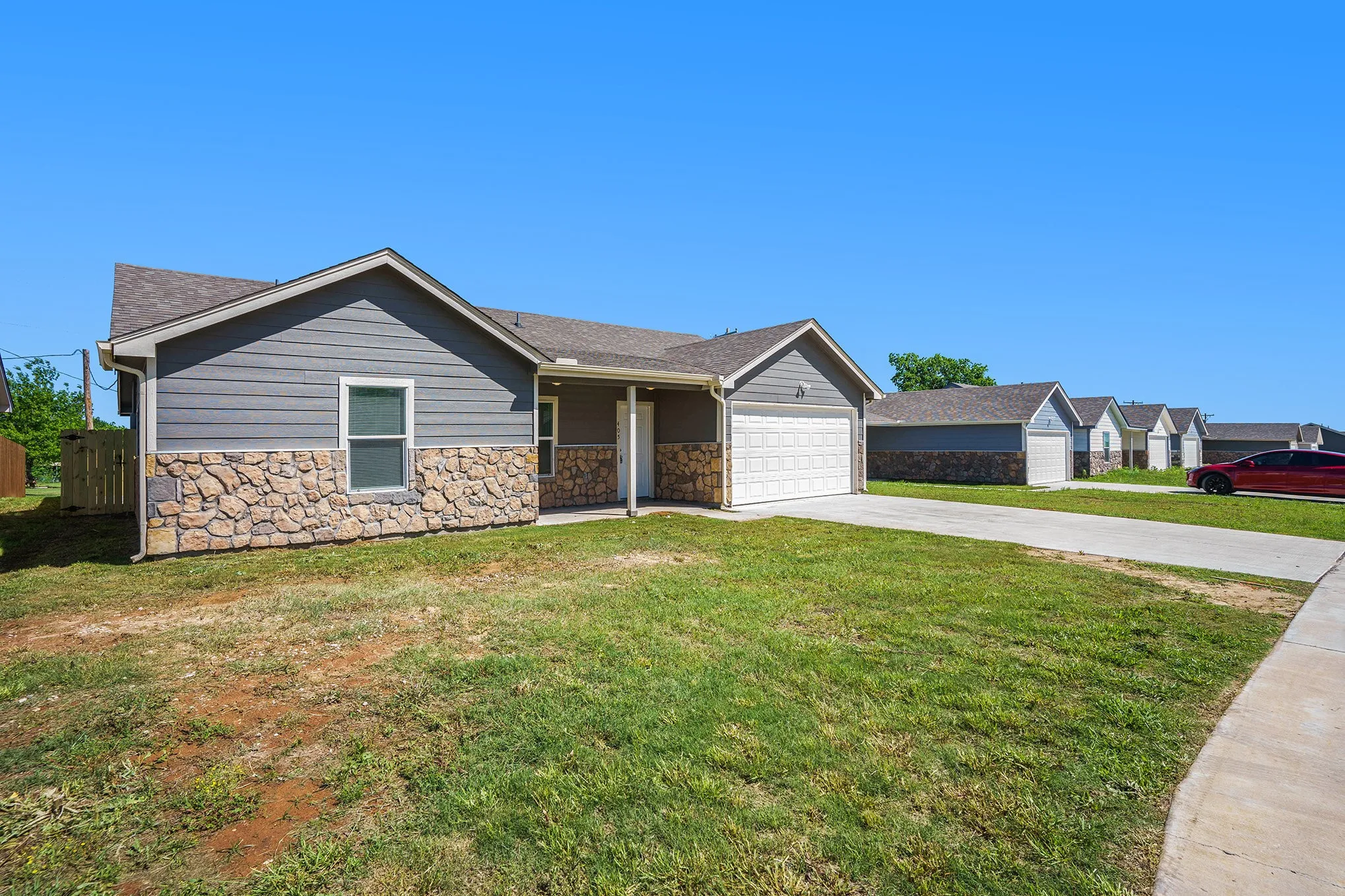 Exterior featuring stone and siding finishes, an attached garage, and a concrete driveway