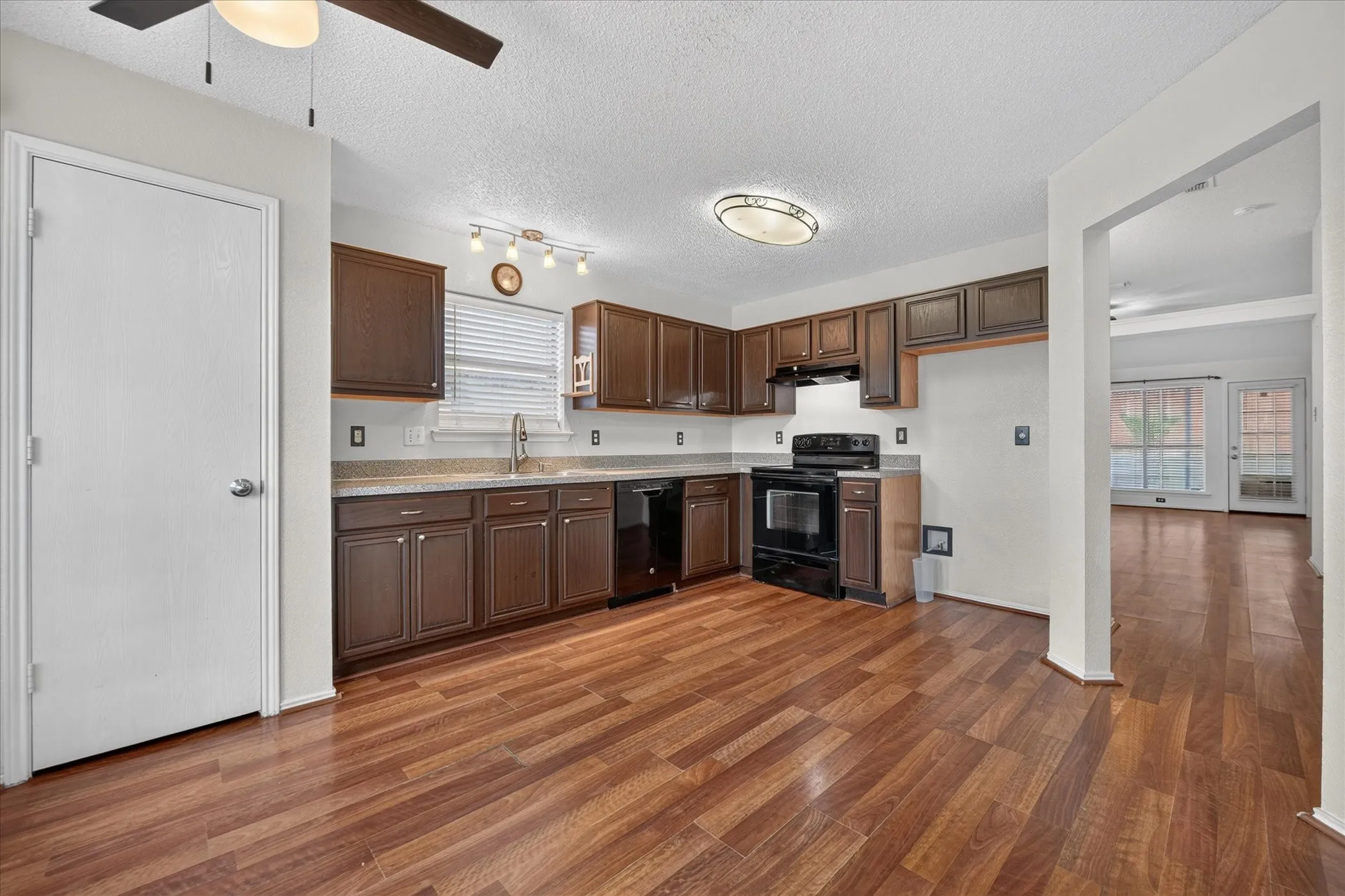 Wide-angle kitchen photo displaying spacious countertops, pantry access, modern finishes, and open sightlines to the main living quarters.