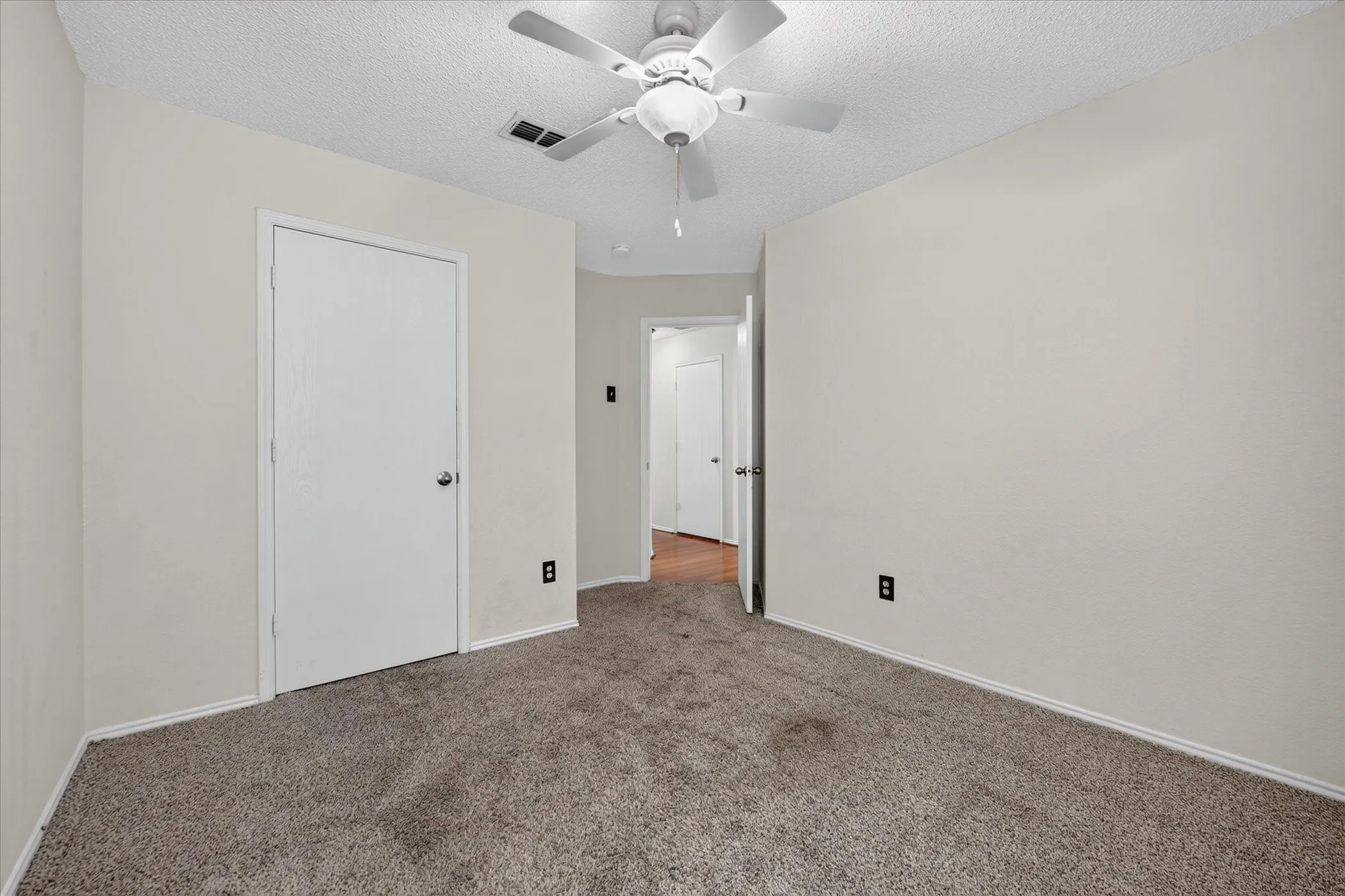 Comfortable primary bedroom retreat with neutral decor, a ceiling fan, plush flooring, and large windows bringing in natural sunshine.  Interior hallway connecting private bedrooms and bath areas, featuring clean architectural lines and modern lighting fixtures.