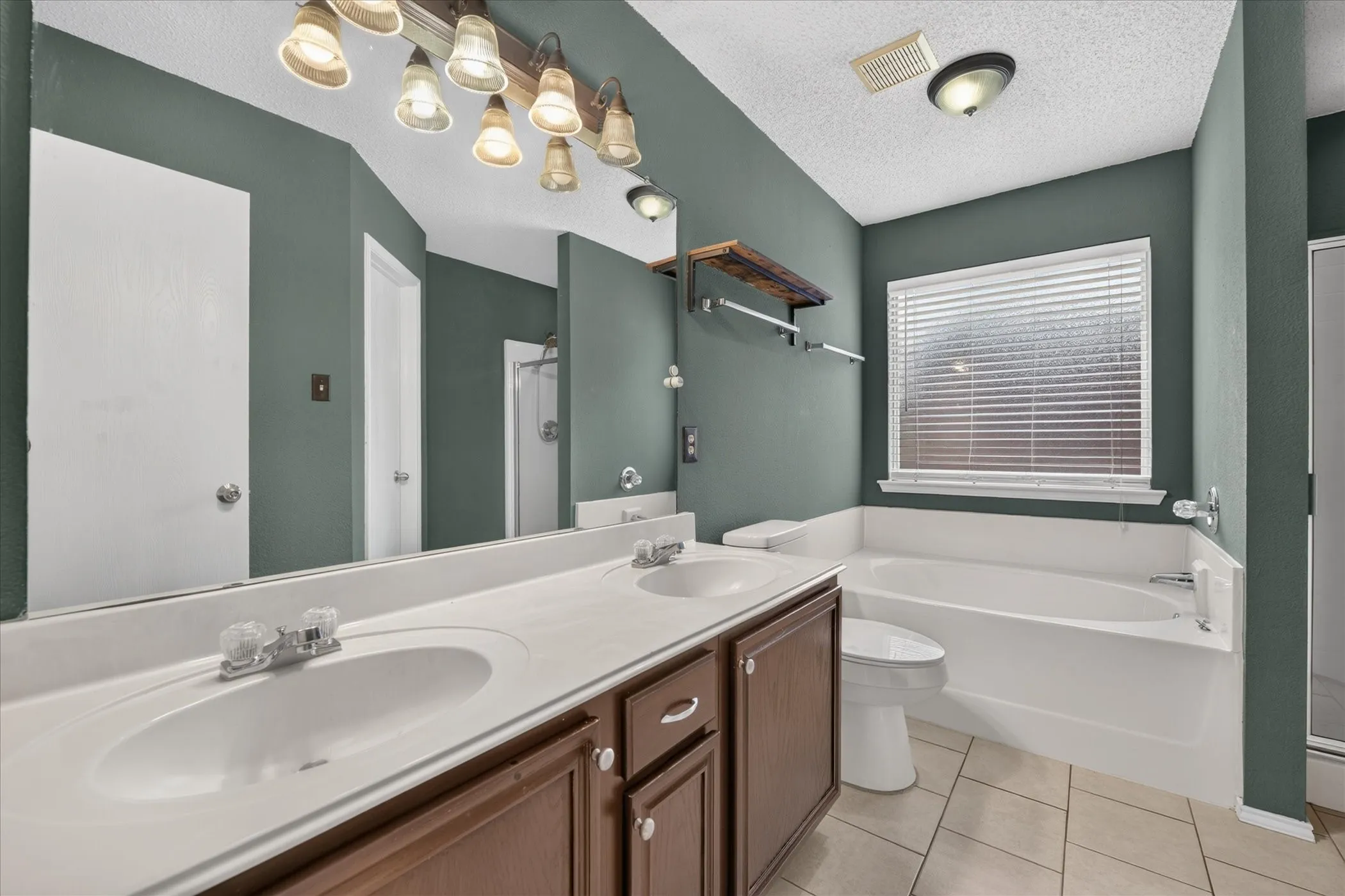 Updated primary bathroom featuring a spacious vanity with storage, clean modern finishes, updated lighting, and quality fixtures.