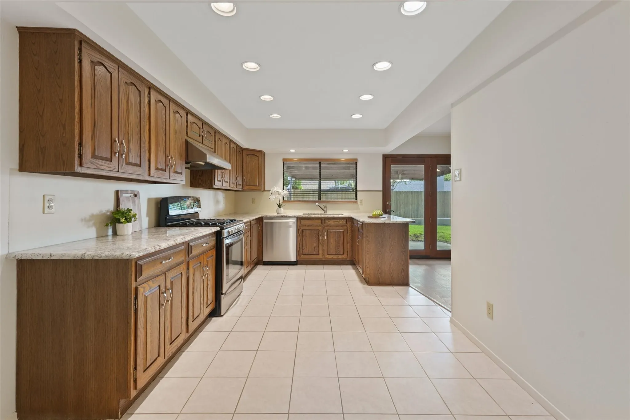 Kitchen featuring wood cabinetry, granite countertops, stainless steel appliances - including gas range, tile flooring, and recessed lighting with dimmer.