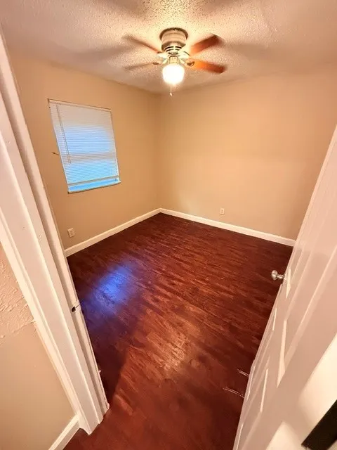 Wood-finish flooring, ceiling fan with integrated lighting, and a window with blinds