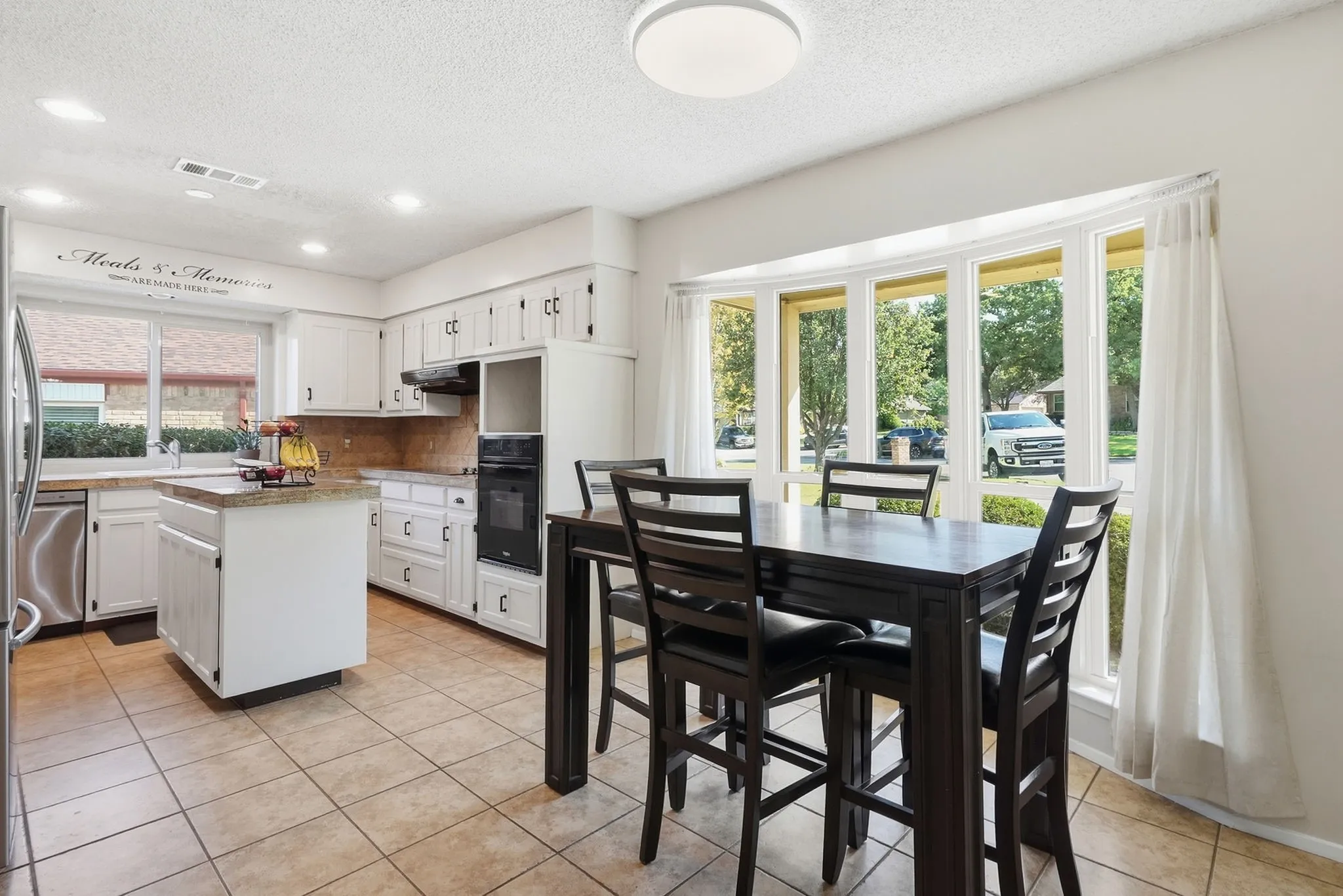 Kitchen featuring white cabinetry, recessed lighting, stainless steel refrigerator, built-in oven, and a bay window