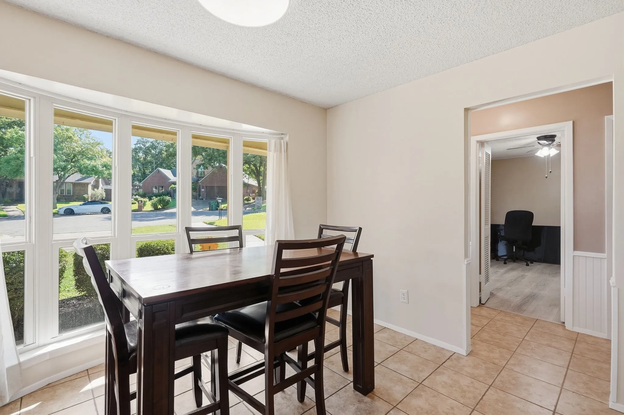 Bay window with multiple panes, tile flooring, interior doorway, and ceiling-mounted light fixture