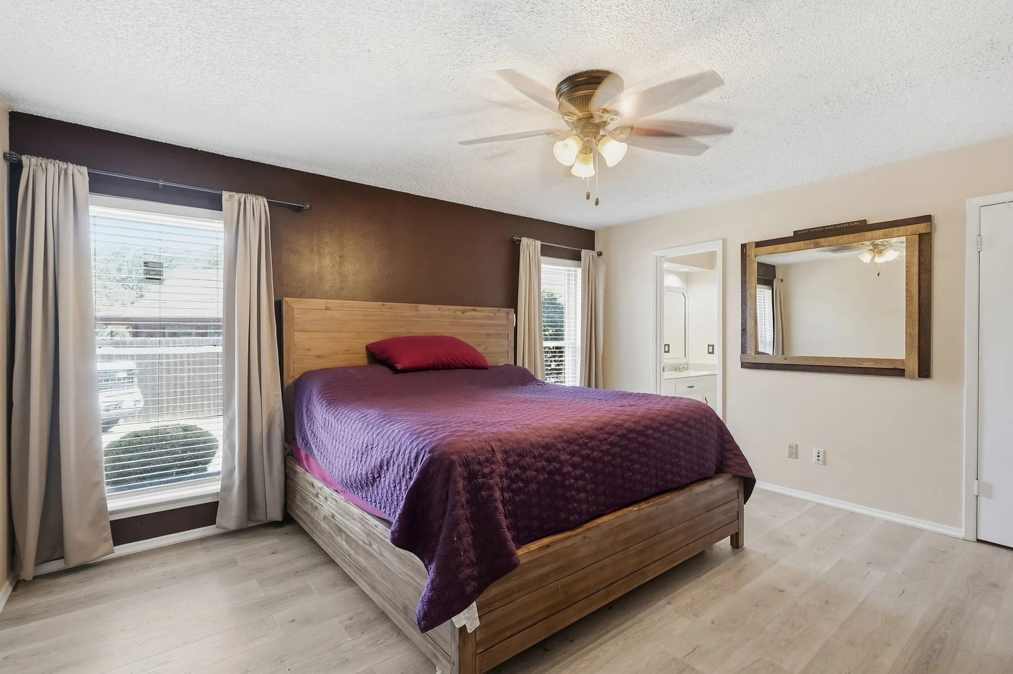Wood-finish flooring, two windows with blinds, and a ceiling fan with light fixture